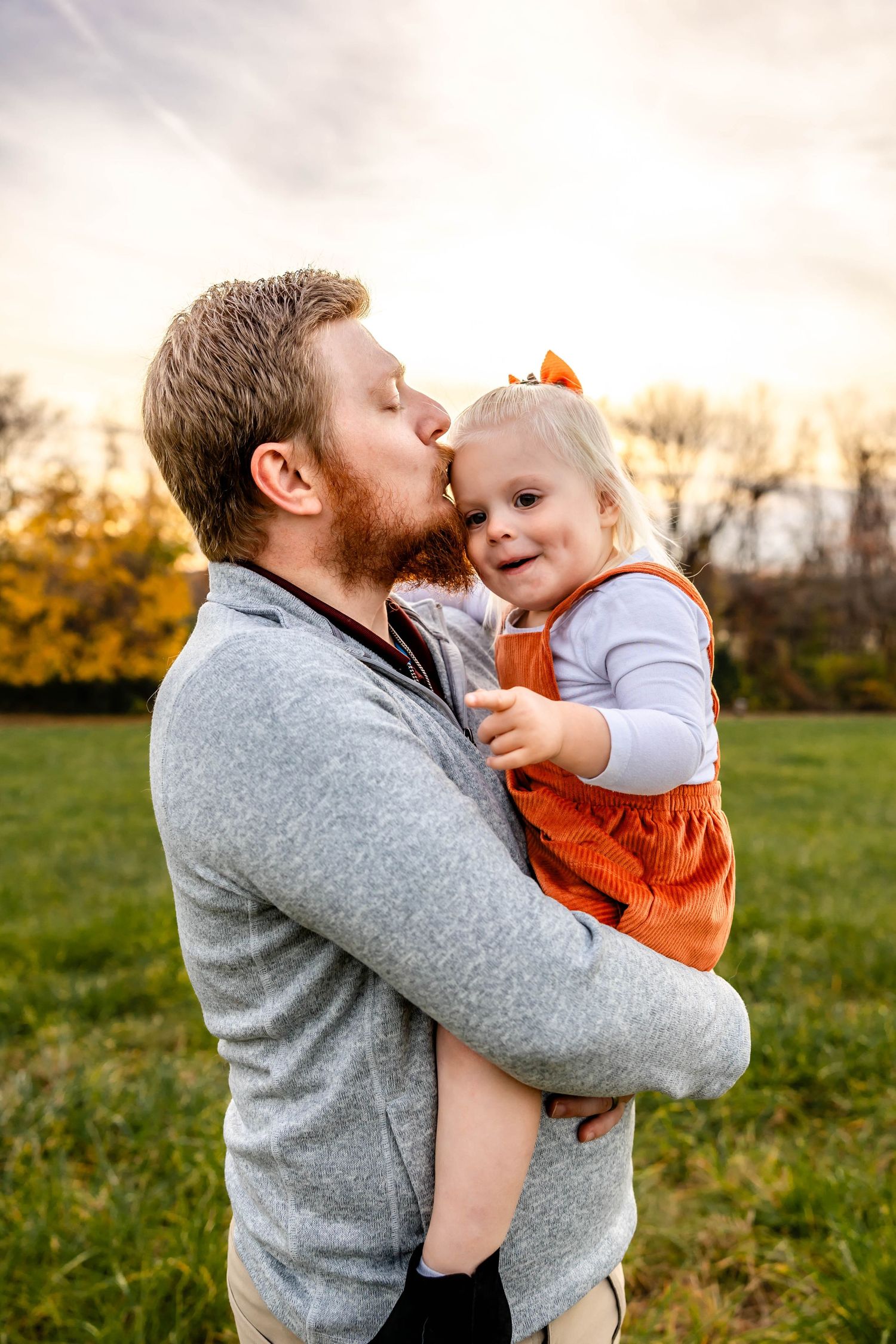 Sweet candid moment showing affection between parent and child outdoors at golden hour.