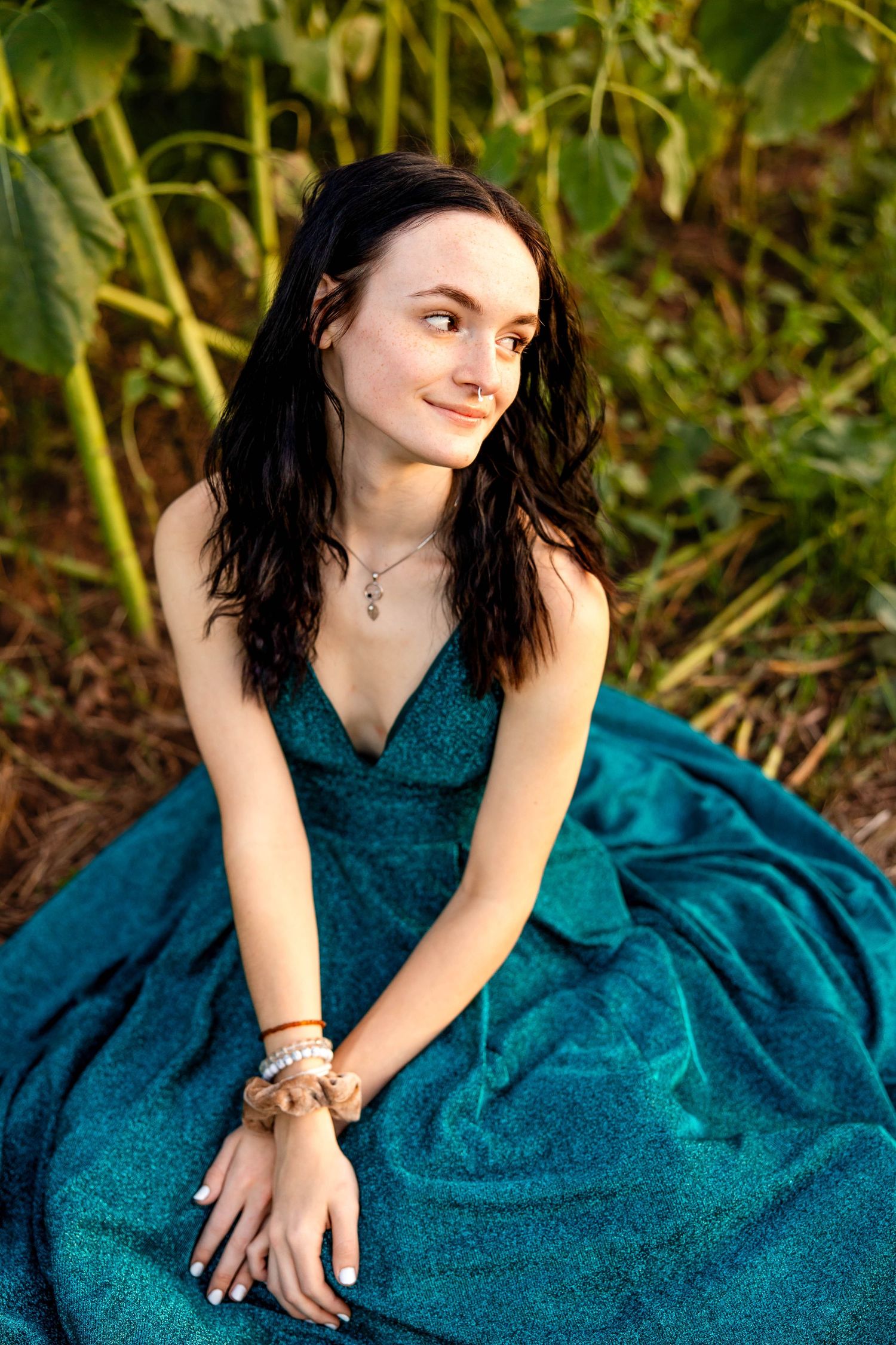 Elegant portrait in deep teal formal dress against lush garden background.