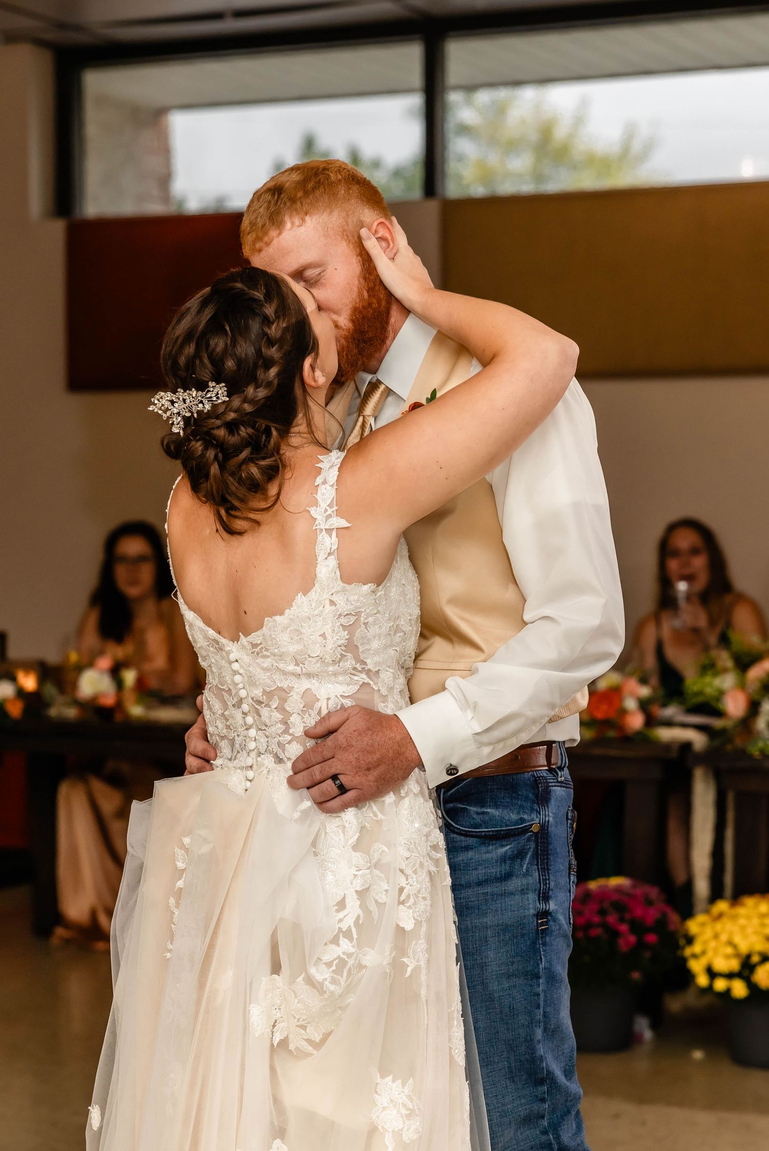 An intimate dance moment at a rustic indoor wedding reception with warm lighting.