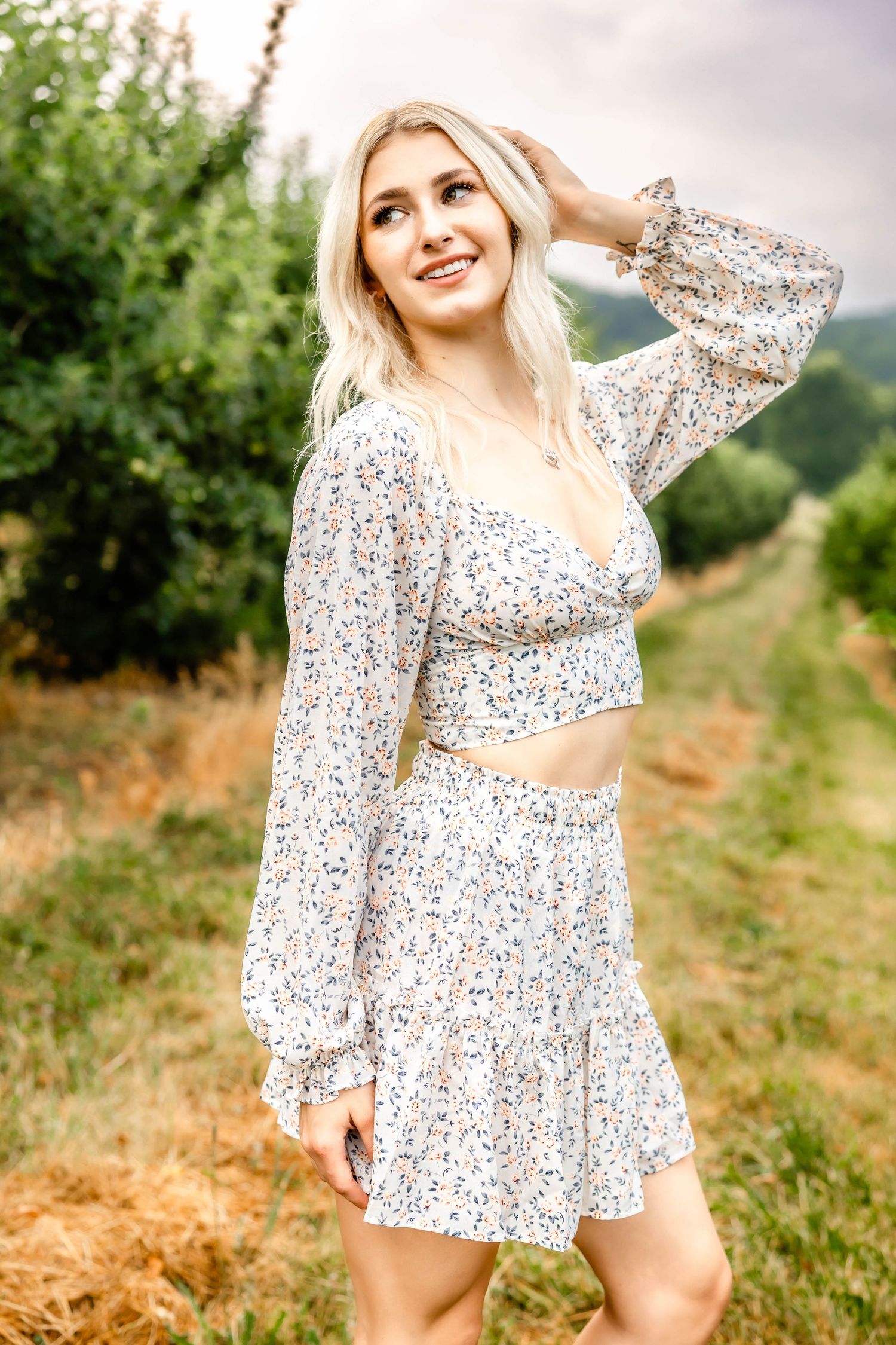 Dreamy summer fashion photography in a white floral outfit against green foliage.