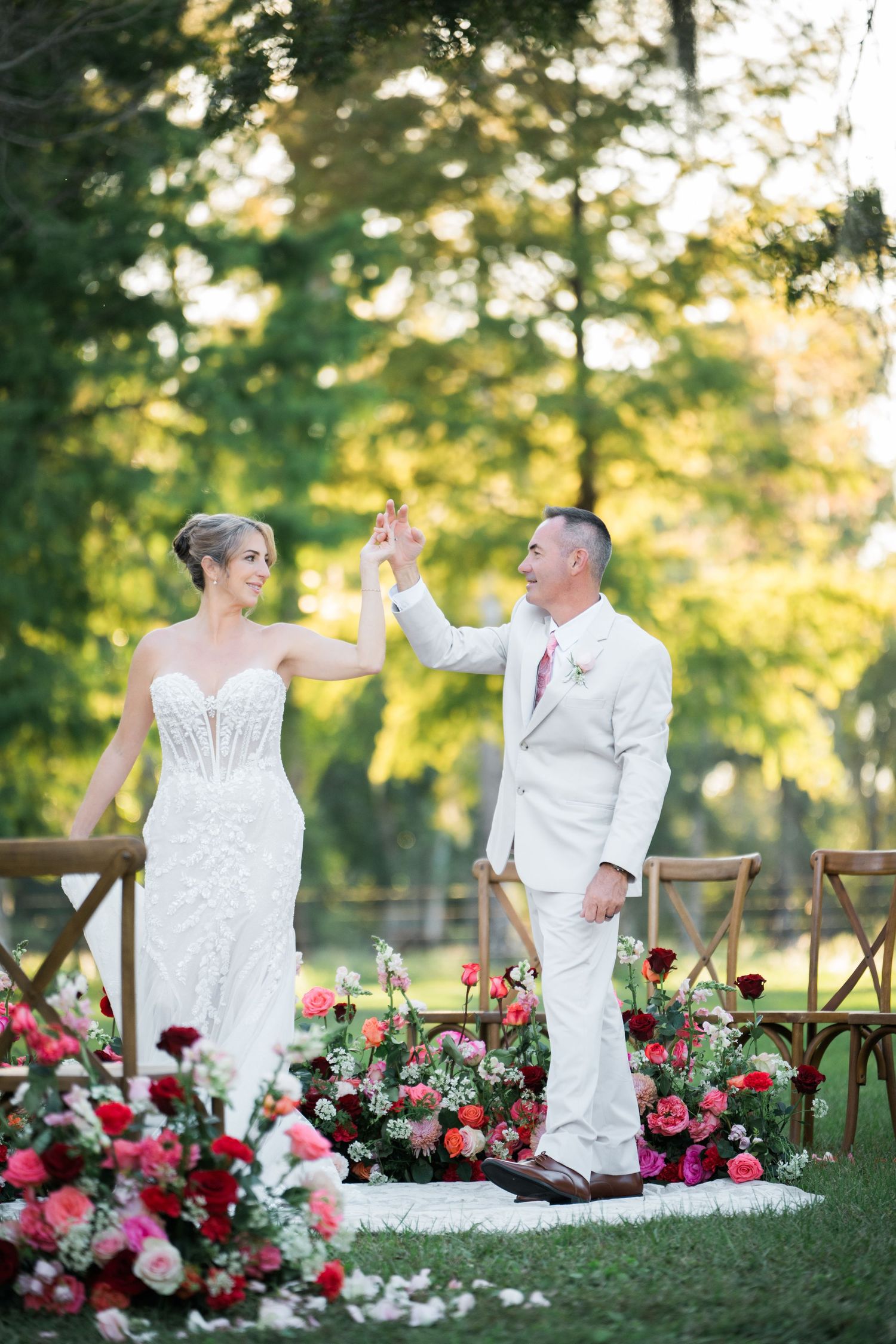 Wedding couple performs playful dance moves among vibrant flowers and garden scenery.