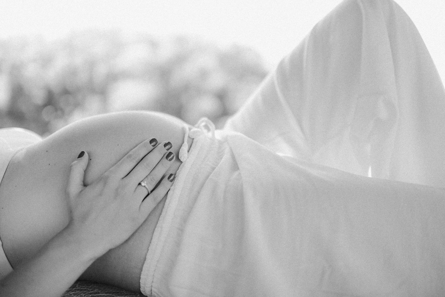 Intimate black and white maternity photography series with soft fabric draping.
