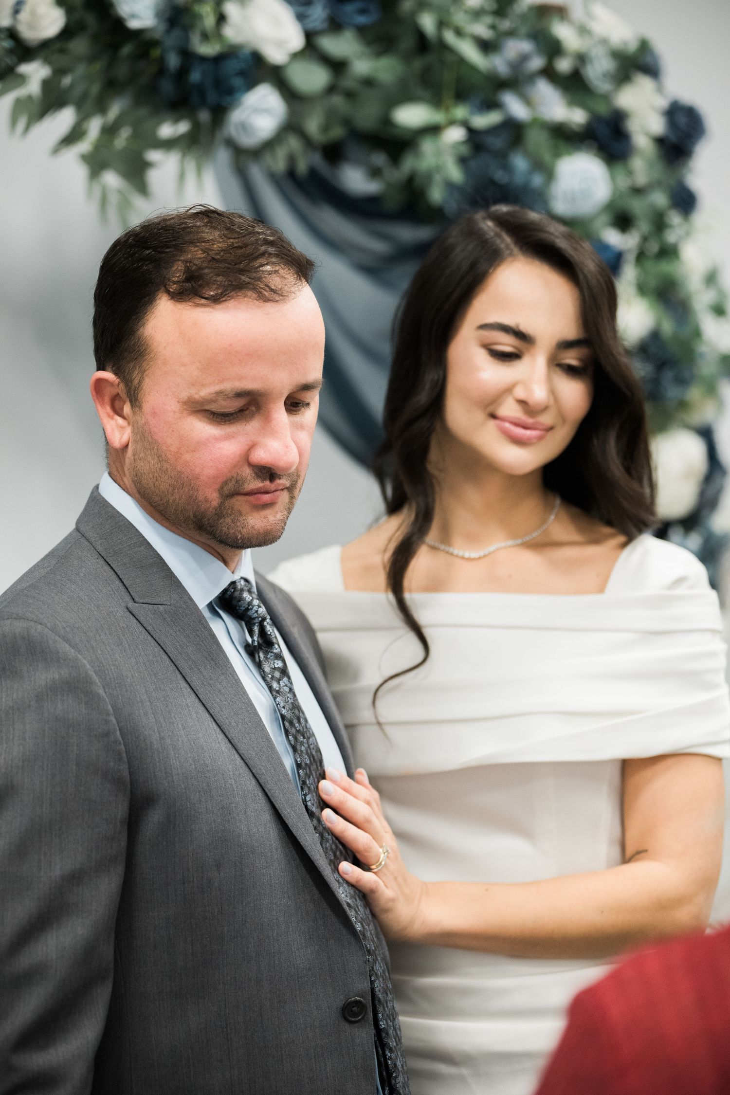 A couple shares tender moments during their wedding ceremony under floral decorations.