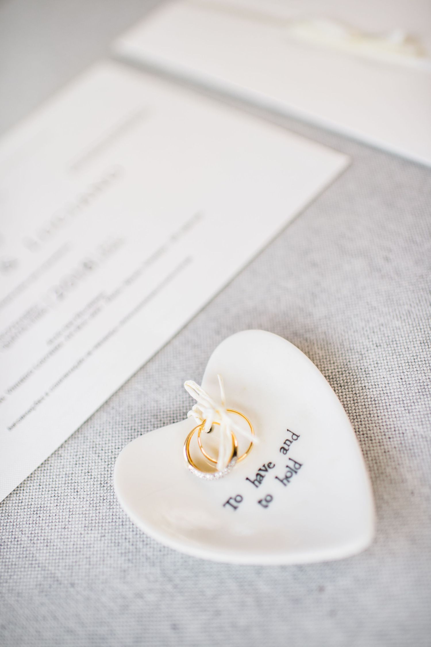 Heart-shaped ceramic dish with handwritten text on light gray linen surface.
