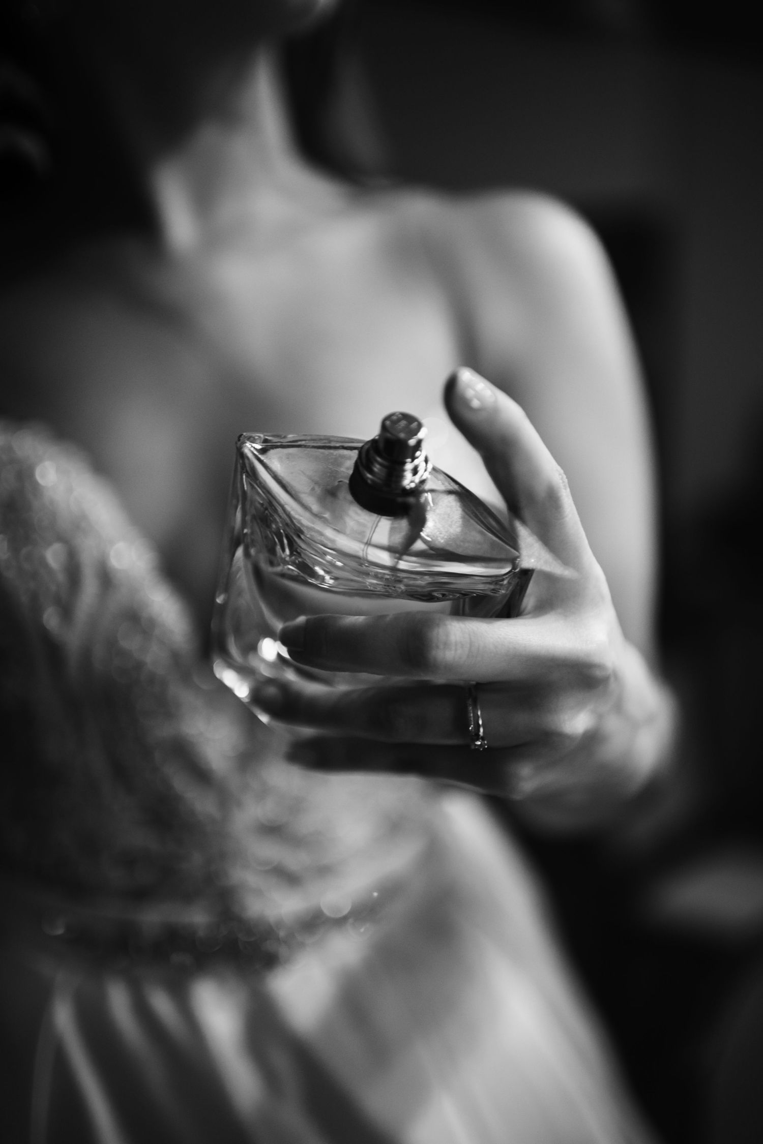 Black and white image of hands holding a perfume bottle with soft focus.