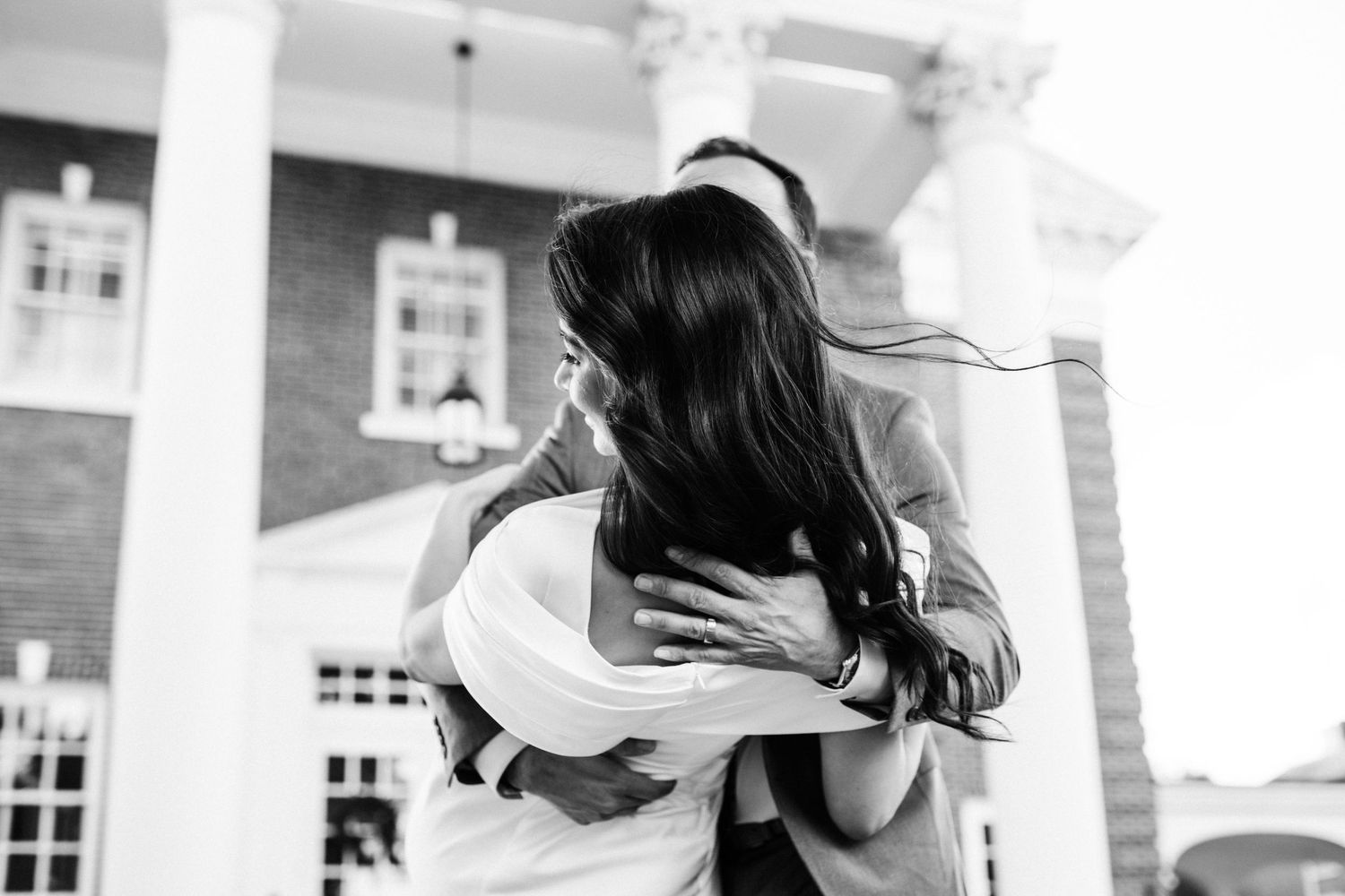A black and white capture of a romantic embrace in front of a columned building.