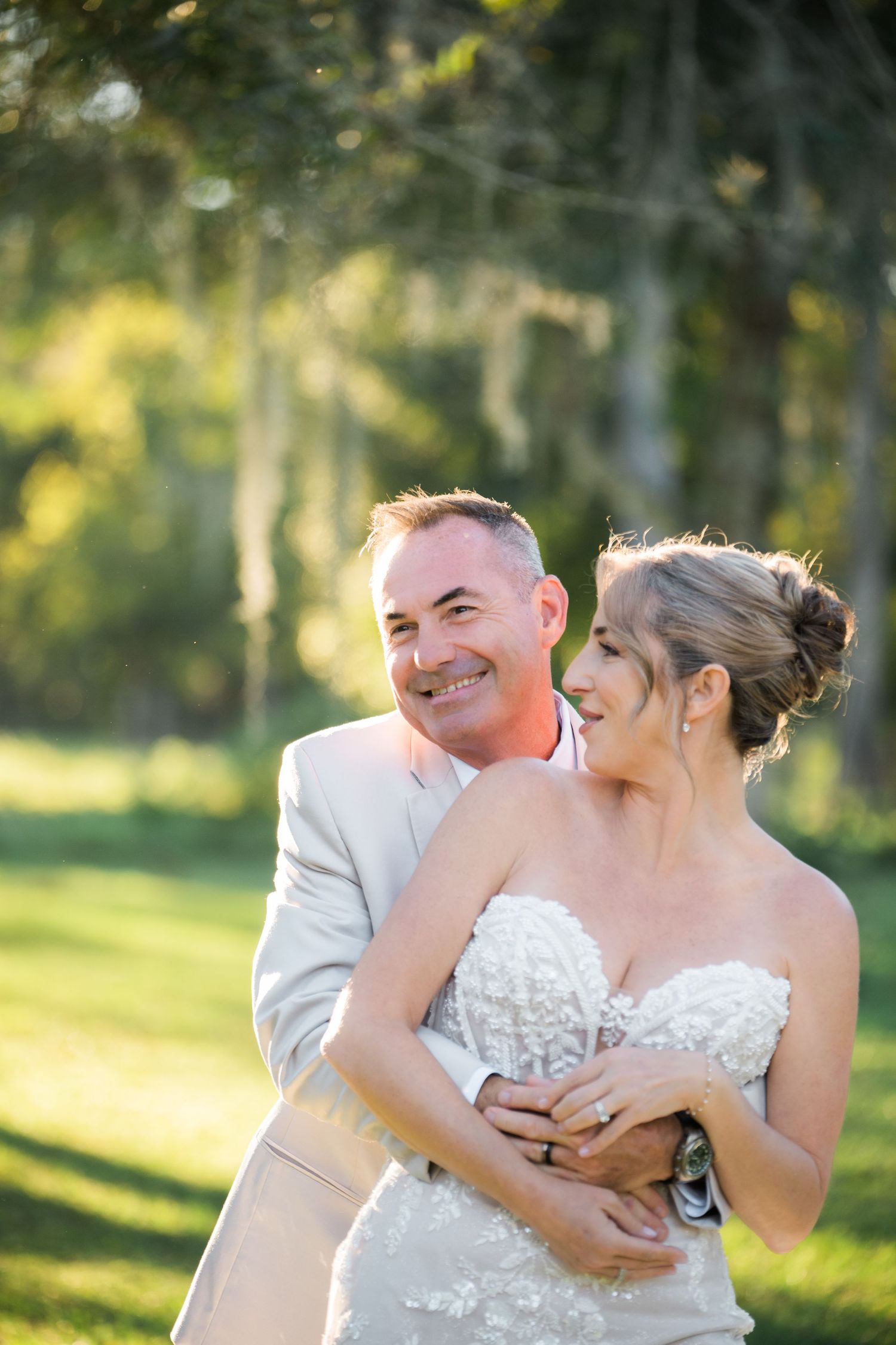 Joyful wedding moment captured in golden sunlight with natural outdoor backdrop.