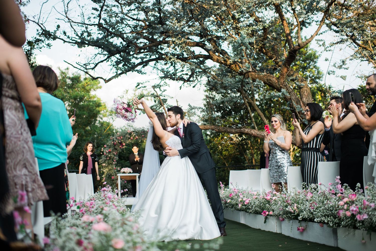 Wedding celebration with guests cheering in a garden setting with floral decorations.