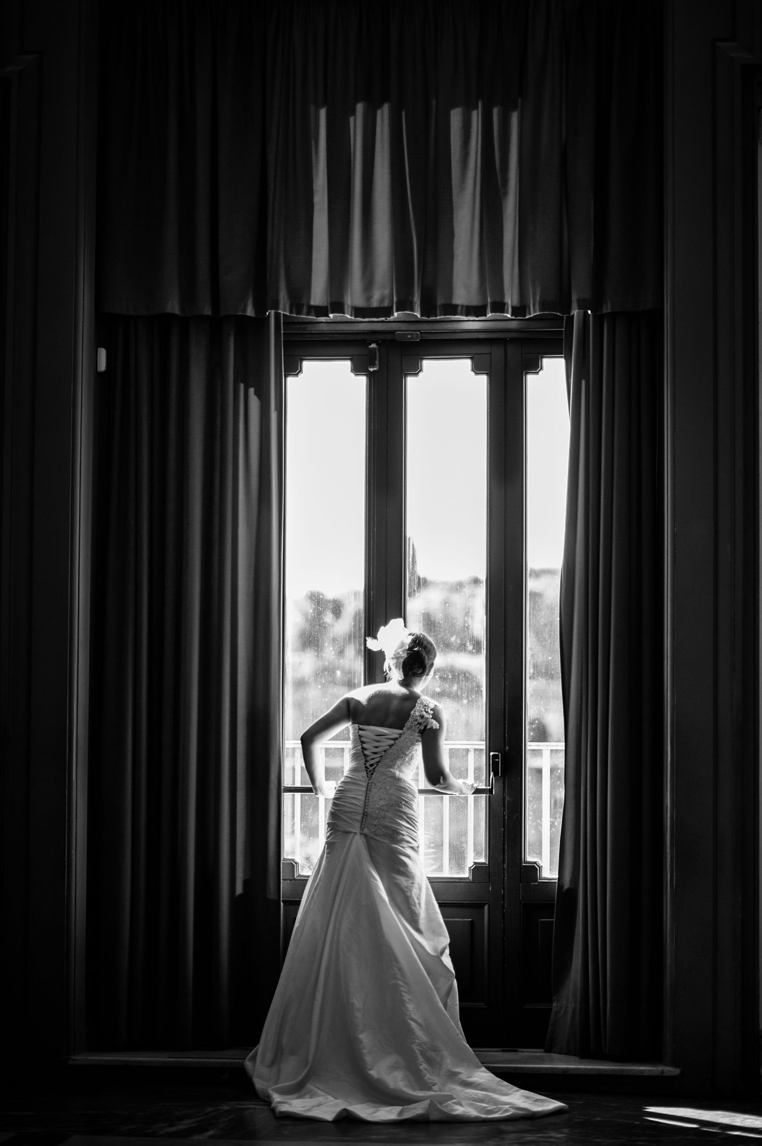 Silhouettes against window light in dramatic black and white wedding photography.