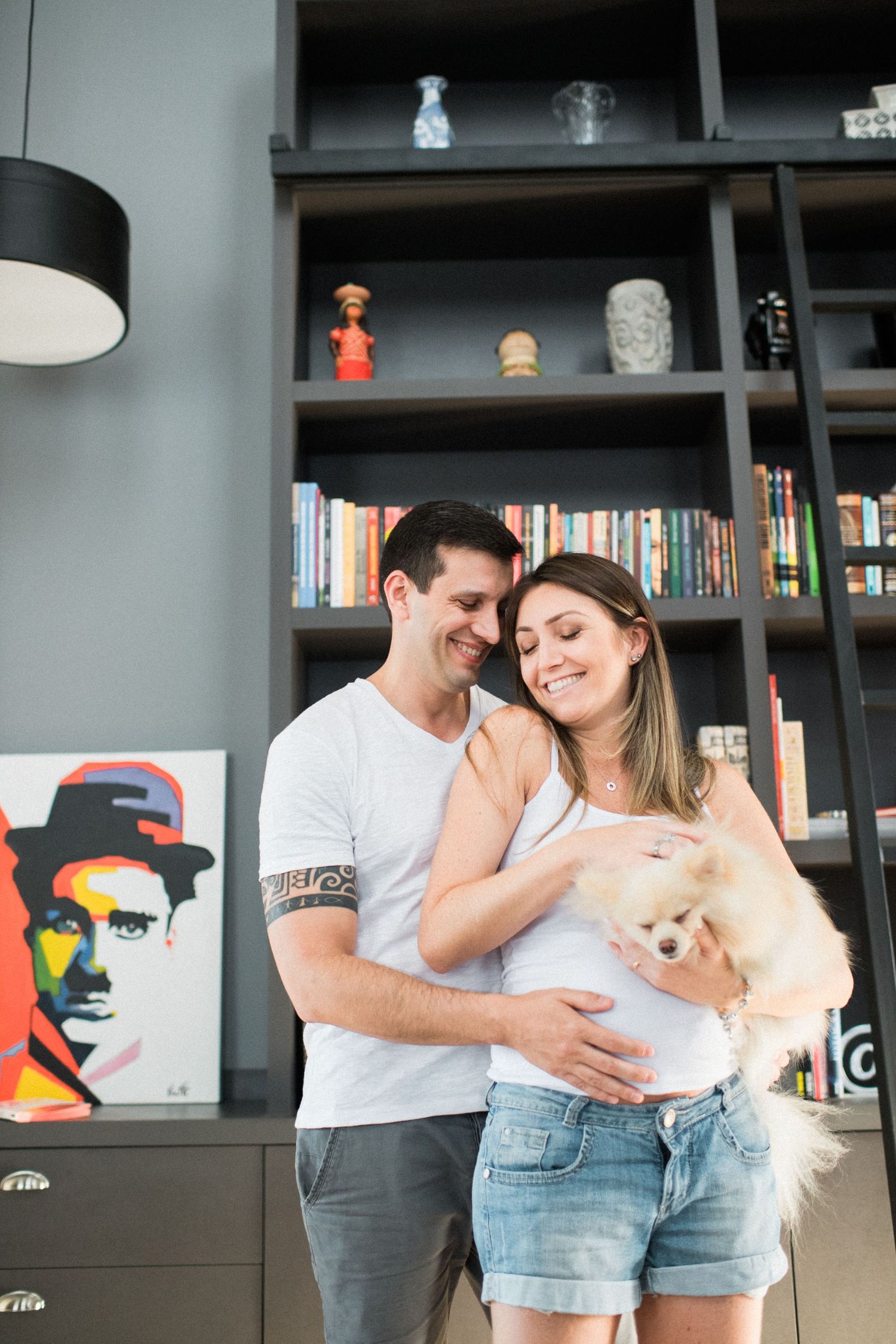 Couple sharing intimate moments in their living room with bookshelves and a small dog.