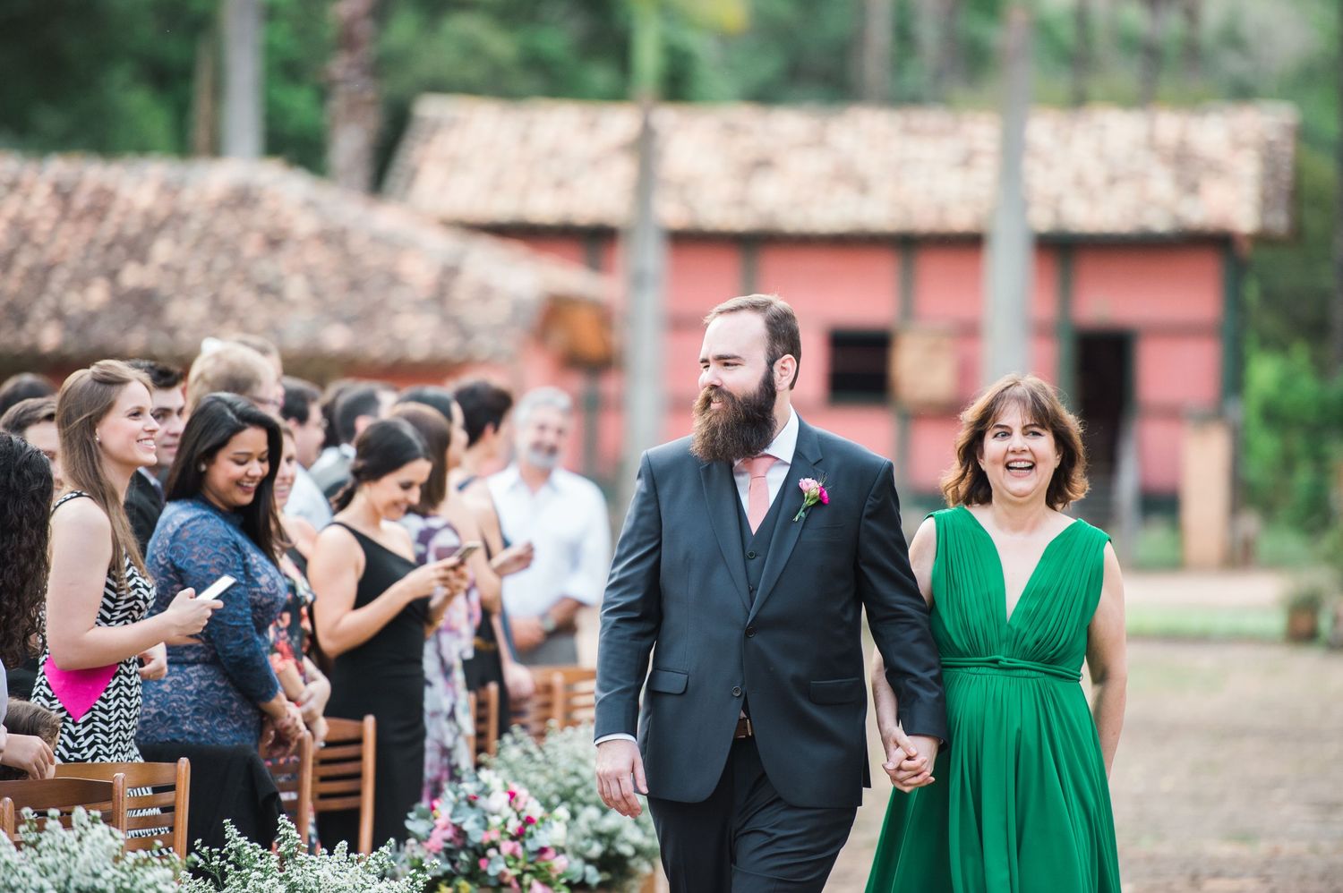 Wedding guests embrace emotionally during an outdoor ceremony at a rustic venue.