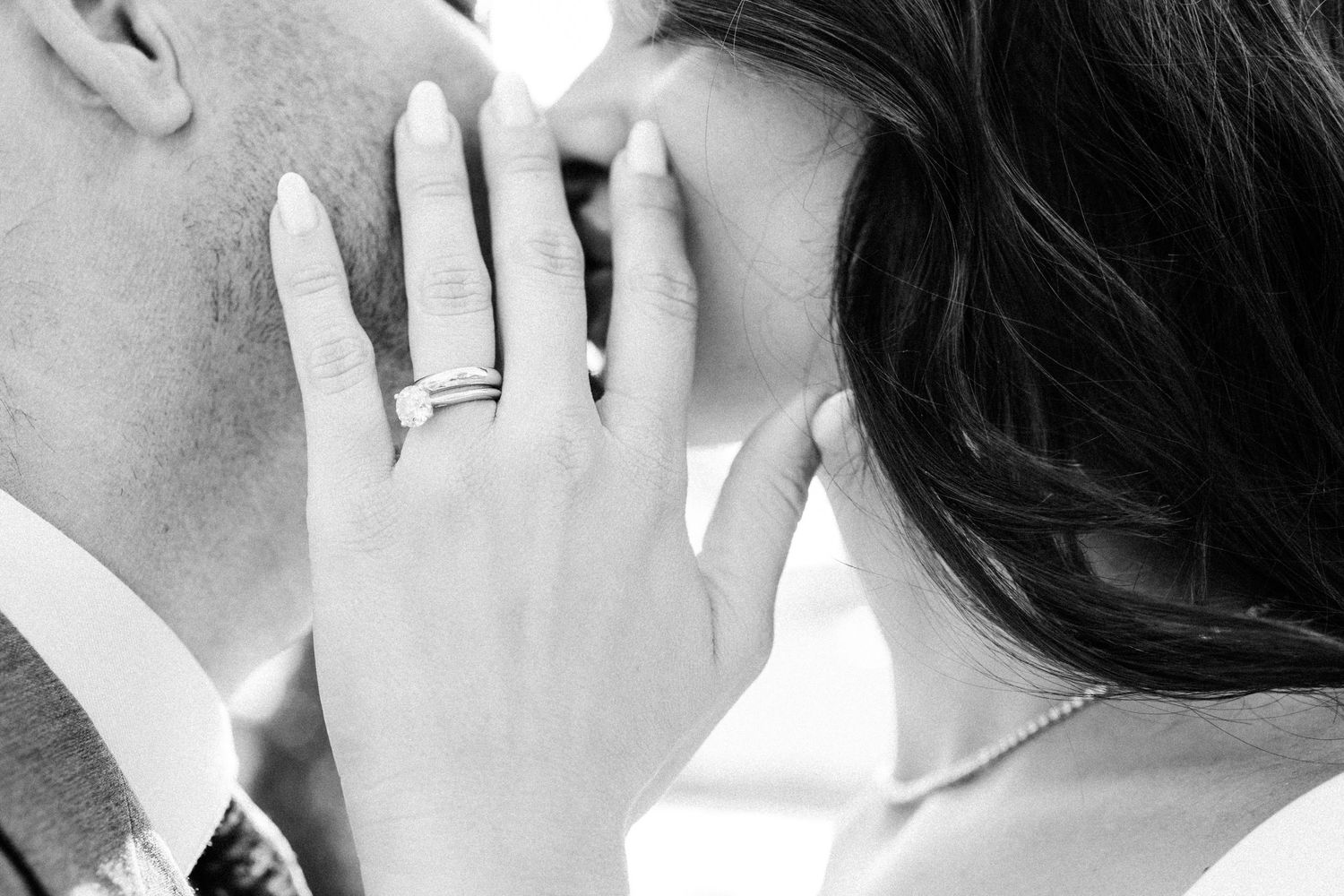 Black and white close-up of hands with wedding ring during an intimate moment.