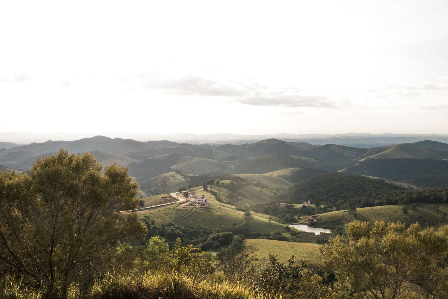 Rolling hills and mountains stretch across a scenic landscape at sunset.