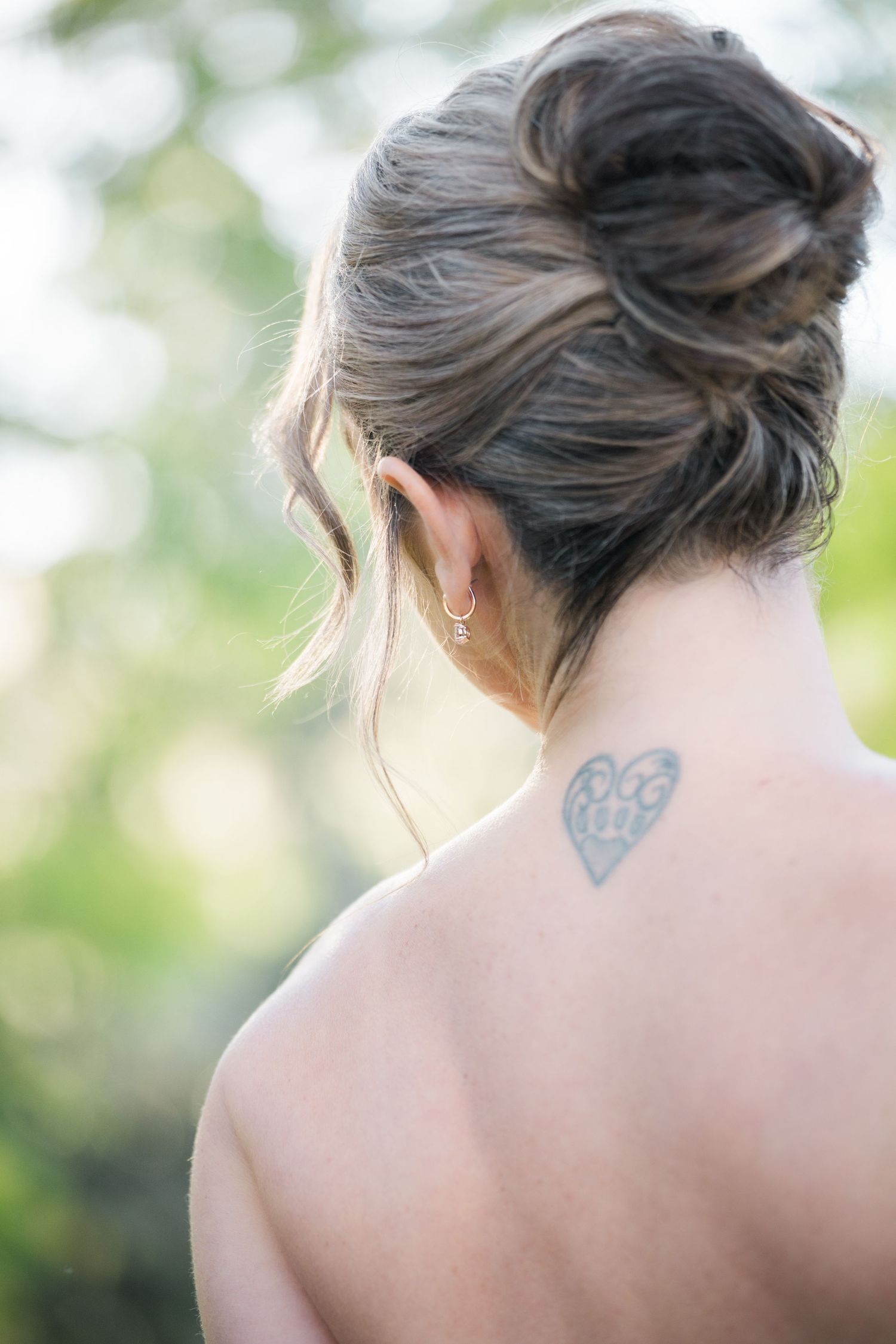 Close-up of bride's upswept hairstyle showing delicate tattoo detail.