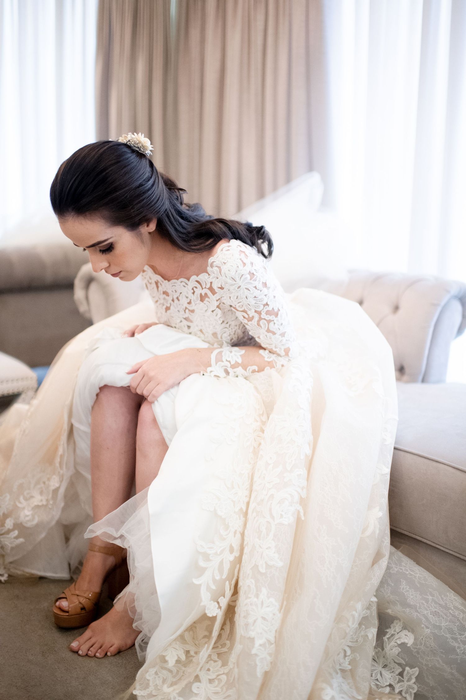 Delicate lace details of a white wedding dress draped on a couch.