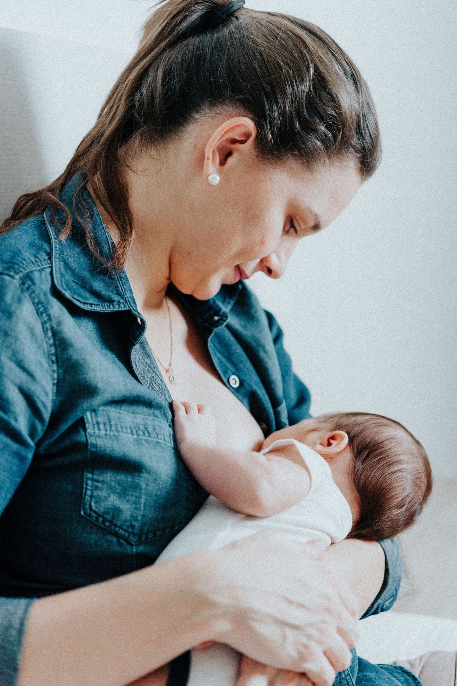 Intimate nursing moment captured in soft, minimalist setting.