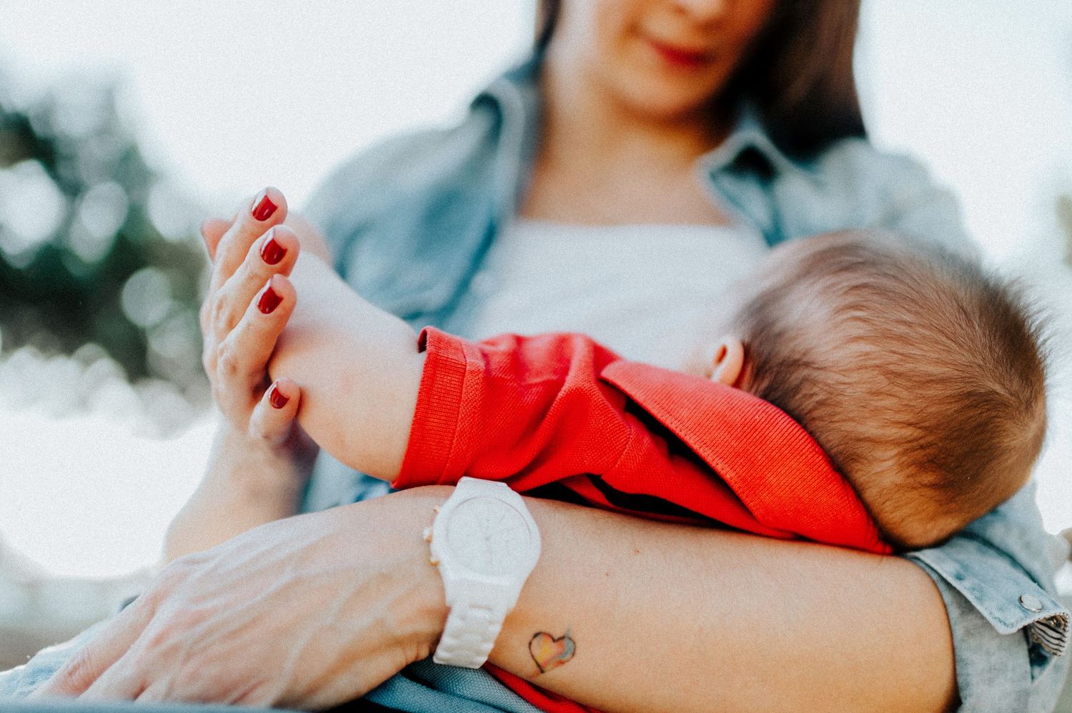 Parent and baby share tender bonding moment in warm sunlit setting.
