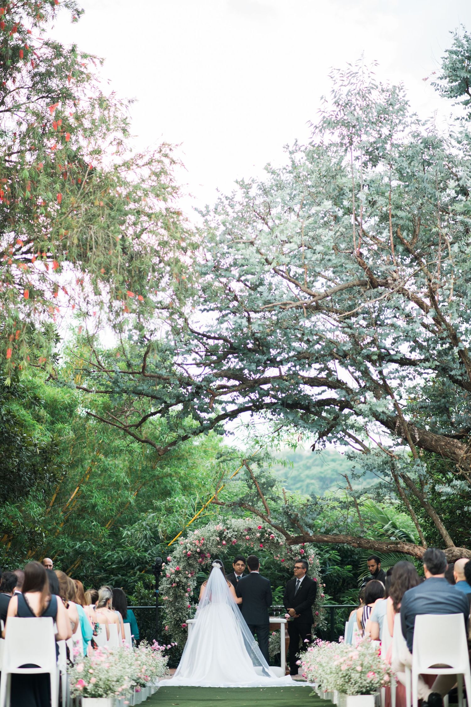 Outdoor wedding ceremony setup under blooming trees with white floral decorations.
