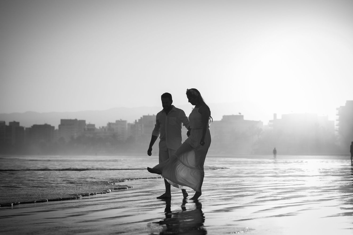 Silhouettes walking along a misty beach at sunset.