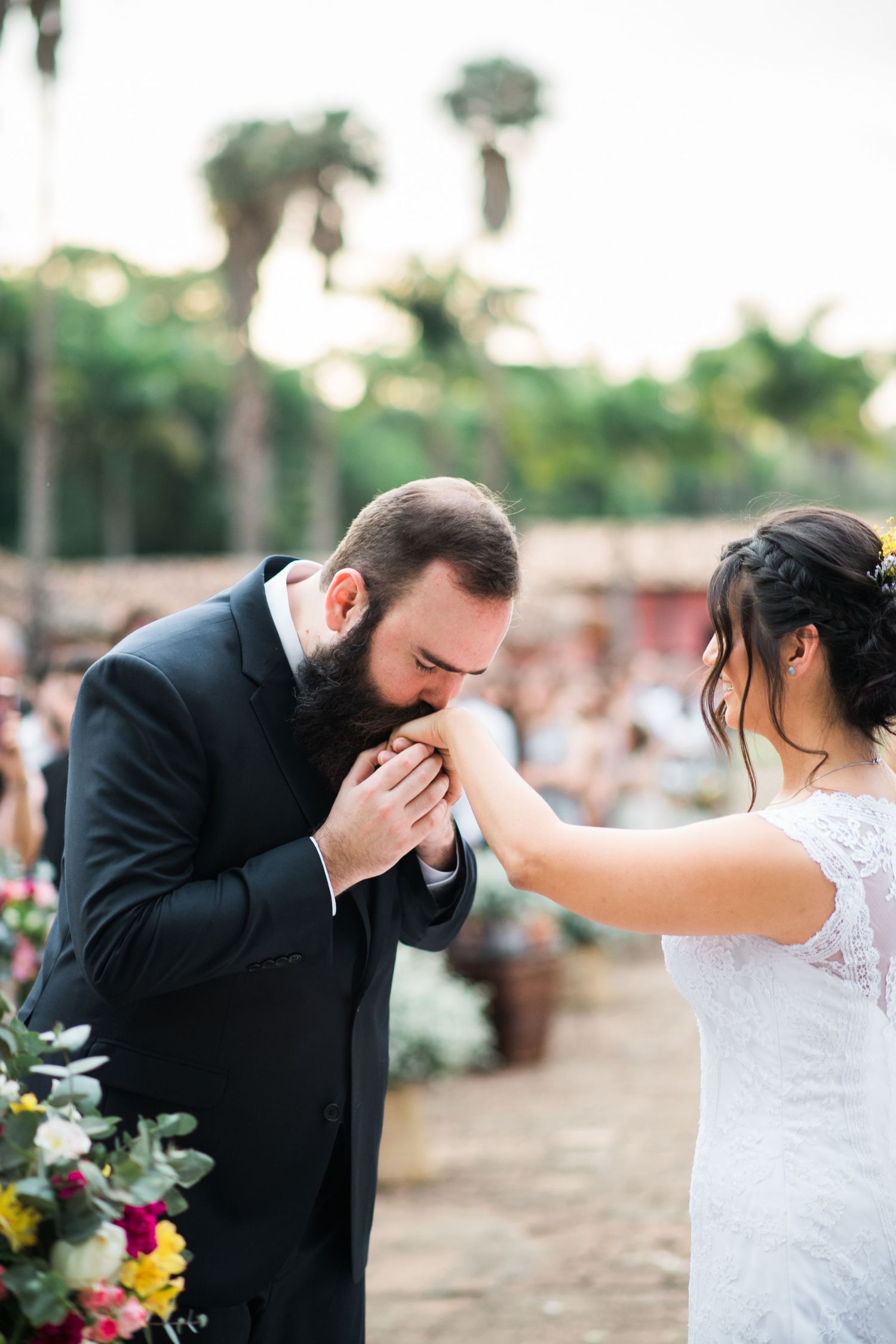 A tender moment during a wedding ceremony as the couple shares a romantic gesture outdoors.