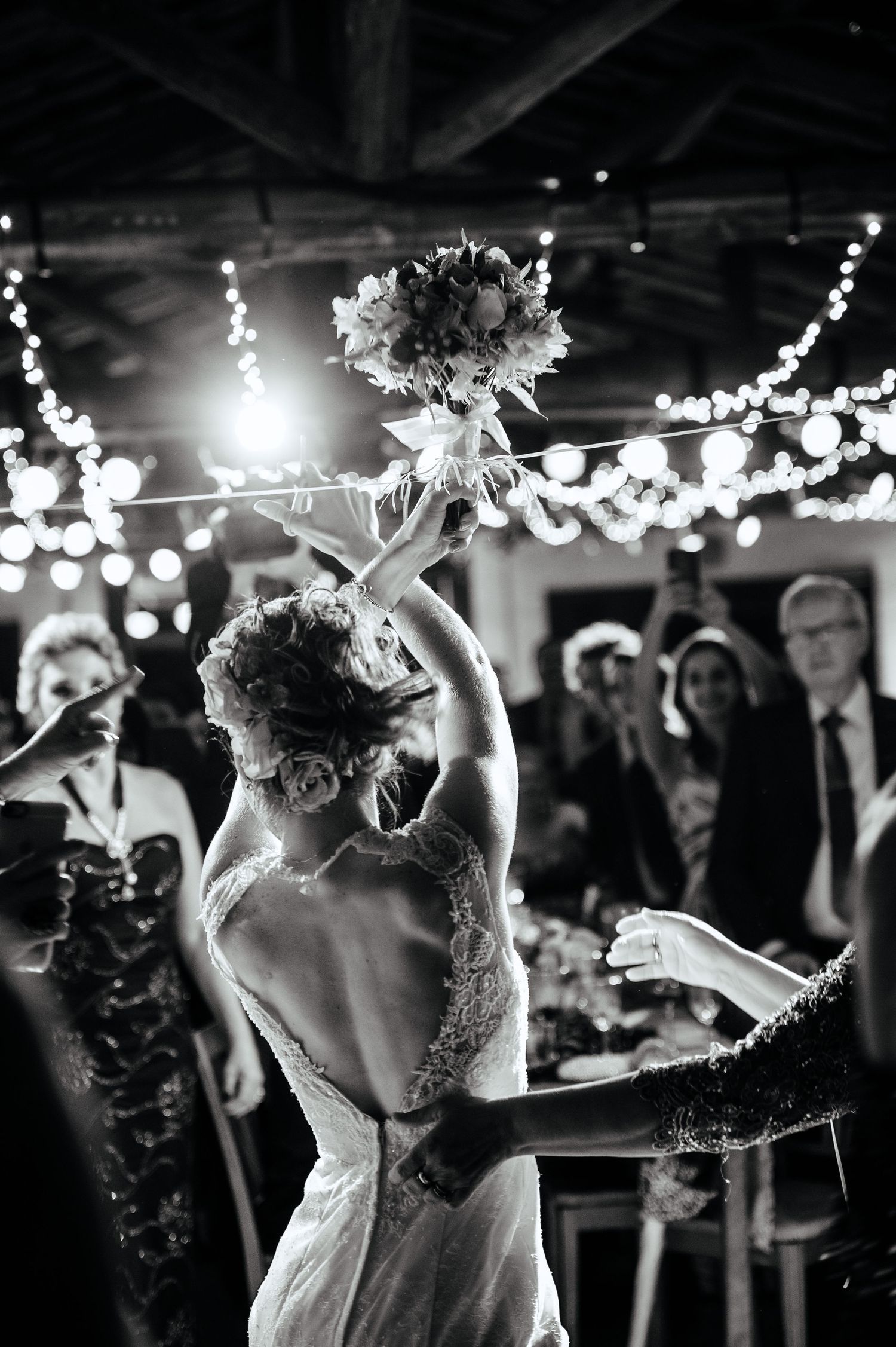 Wedding celebration under twinkling lights with dancing and joyful movement.
