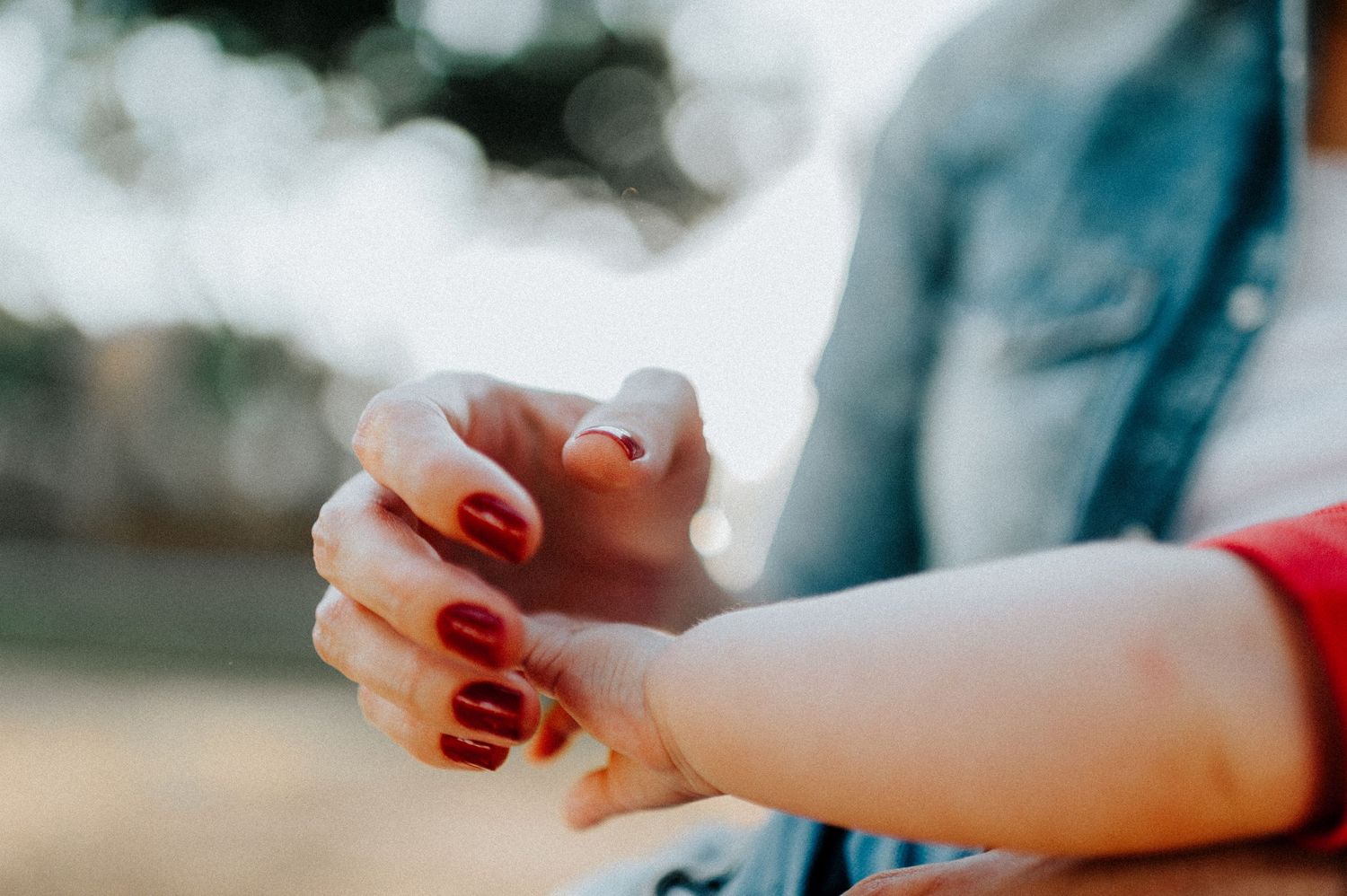 Hands reaching toward each other against blurred outdoor background.