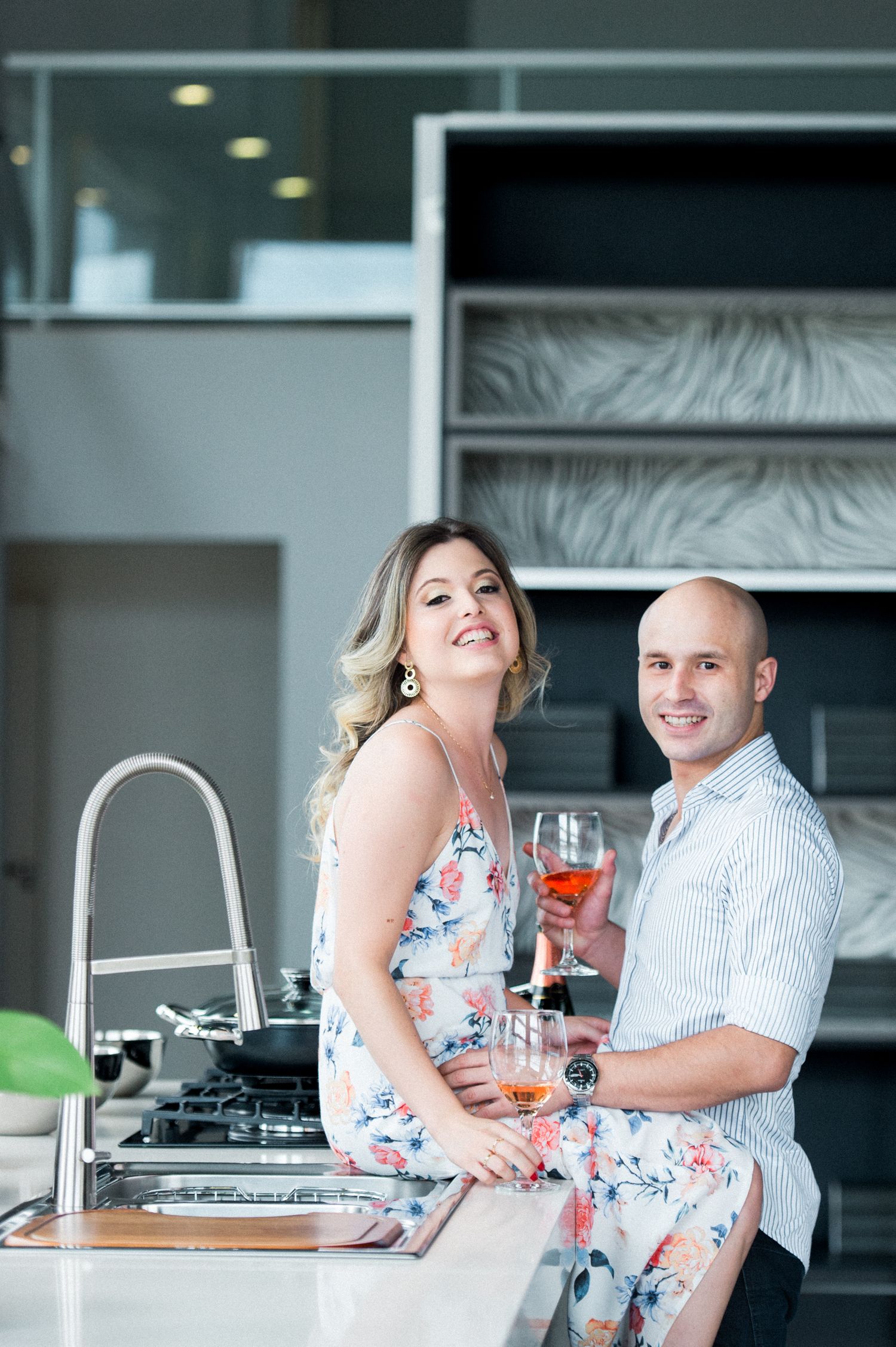 Romantic couple sharing drinks and laughter in contemporary kitchen.