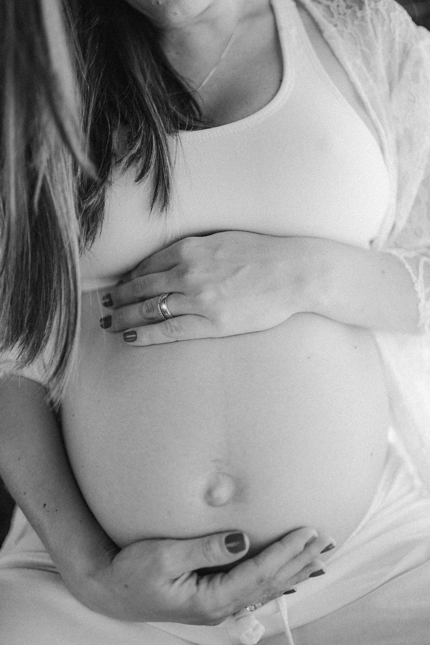 Close-up black and white maternity photos showing a pregnant belly with hands gently resting.
