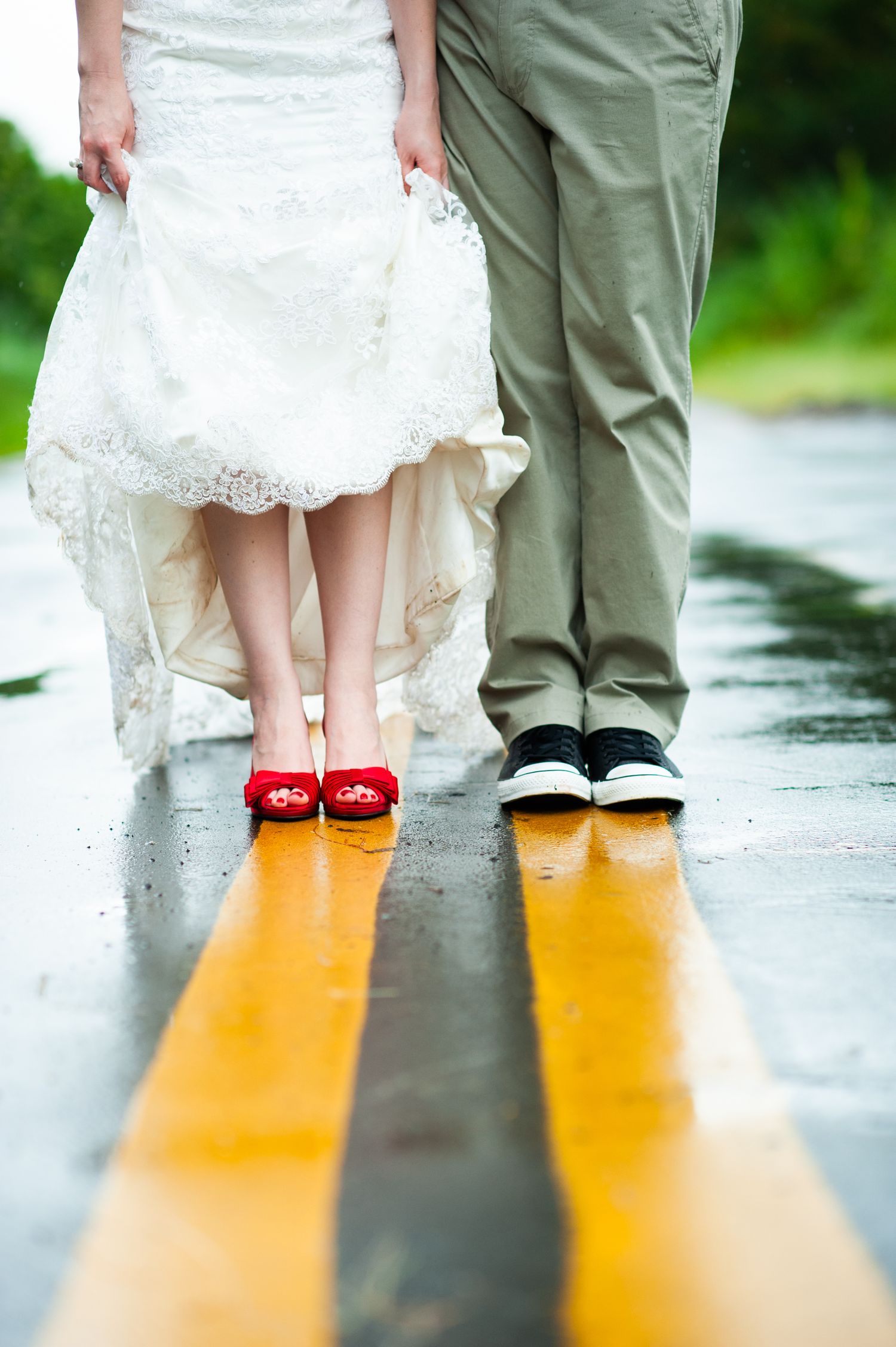 Wedding photo detail showing bride and groom's shoes on yellow road markings.