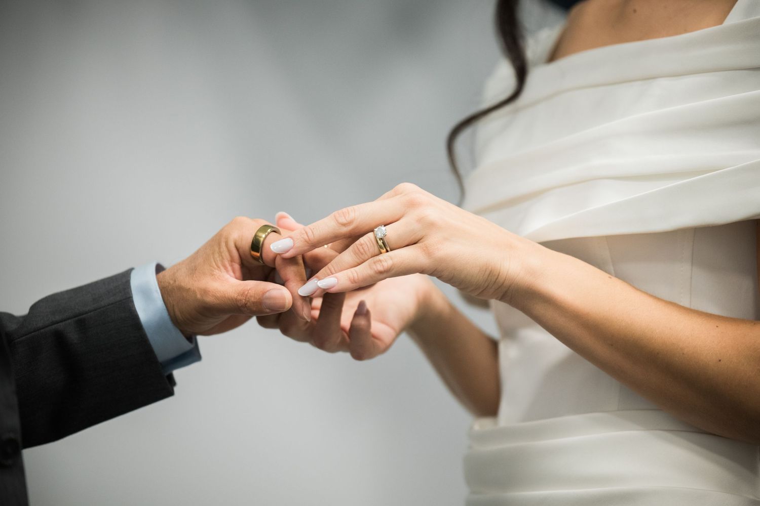 Close-up of hands exchanging wedding rings during an intimate ceremony.