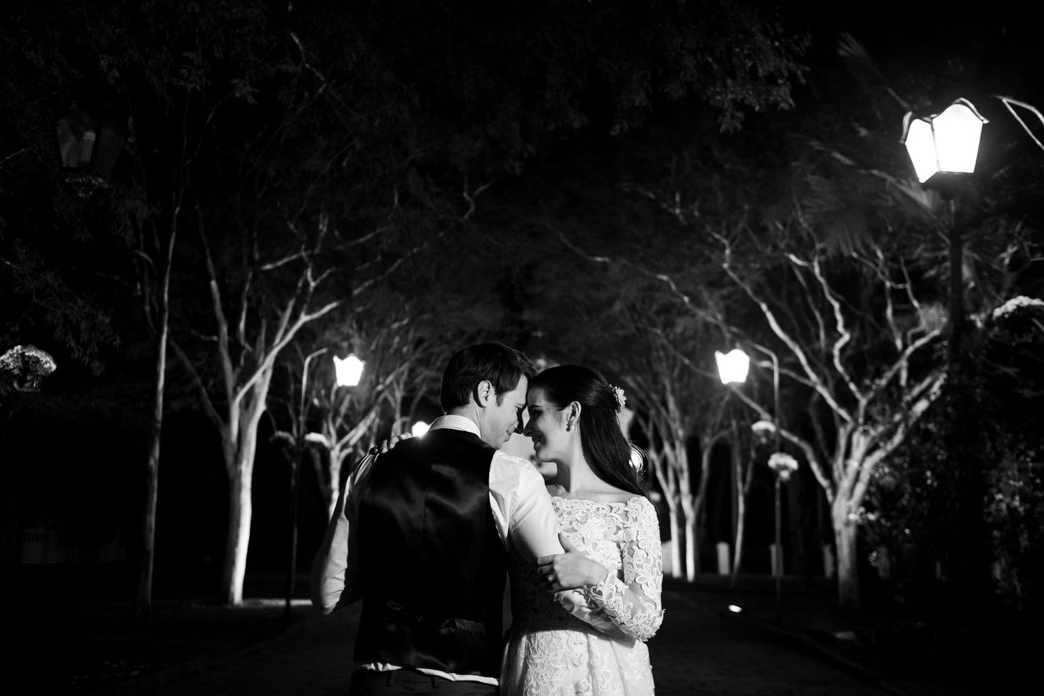 Illuminated trees create a magical nighttime wedding ceremony backdrop with string lights.