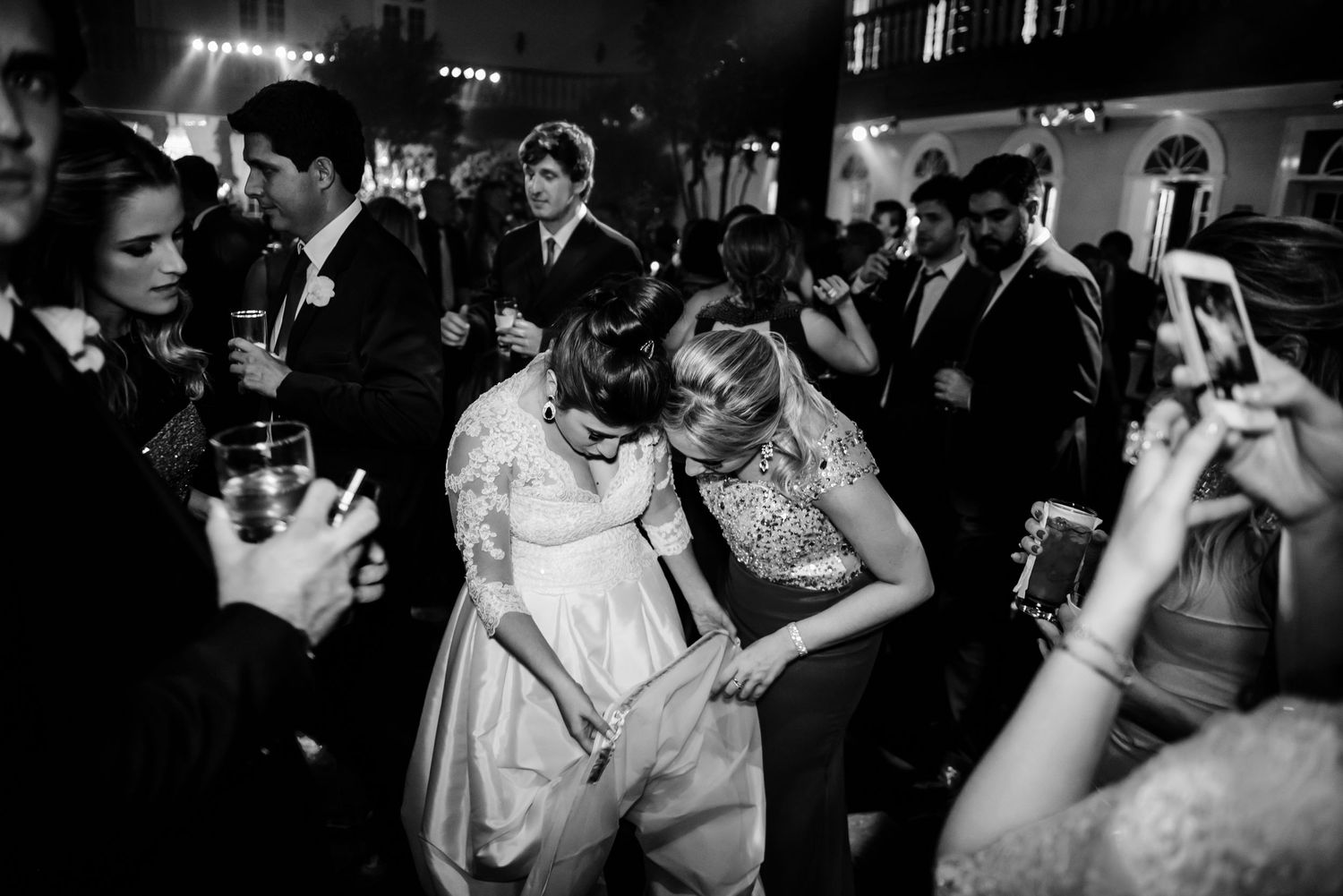 Wedding reception dance floor filled with guests celebrating in a dimly lit venue.