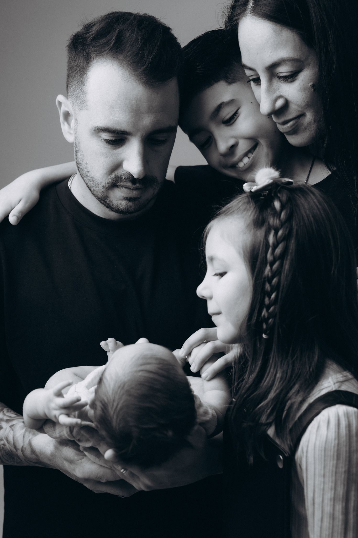 Intimate black and white family portraits showing affectionate moments with a baby.