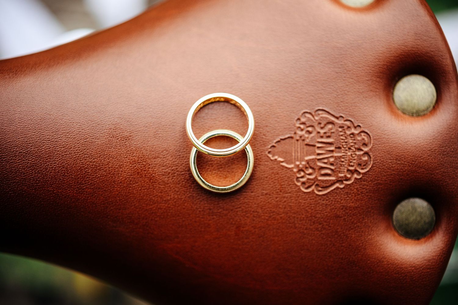Wedding rings displayed on brown leather with decorative embossing.