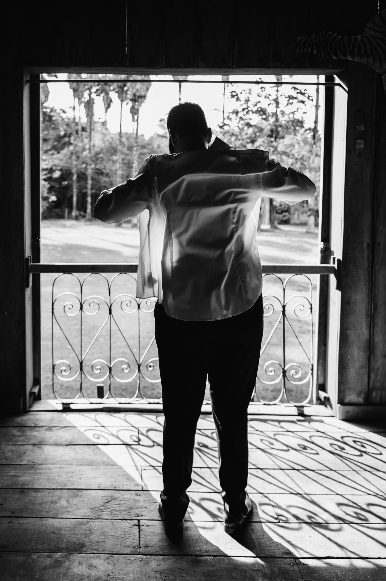 Silhouette of a person standing at a vintage window with ornate iron details.