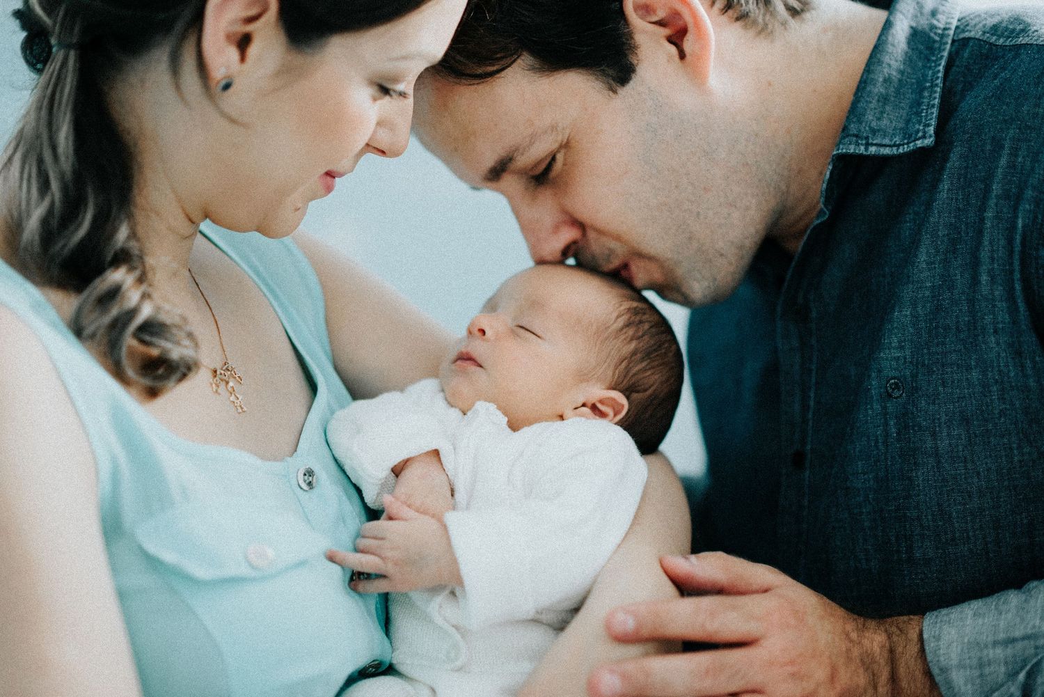 Parents sharing tender moments with their newborn baby in nursery setting.