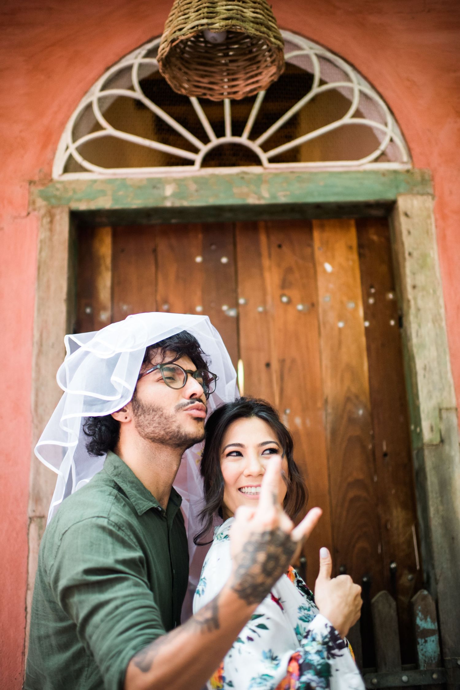 A playful moment captured in front of a rustic orange door with decorative ironwork.