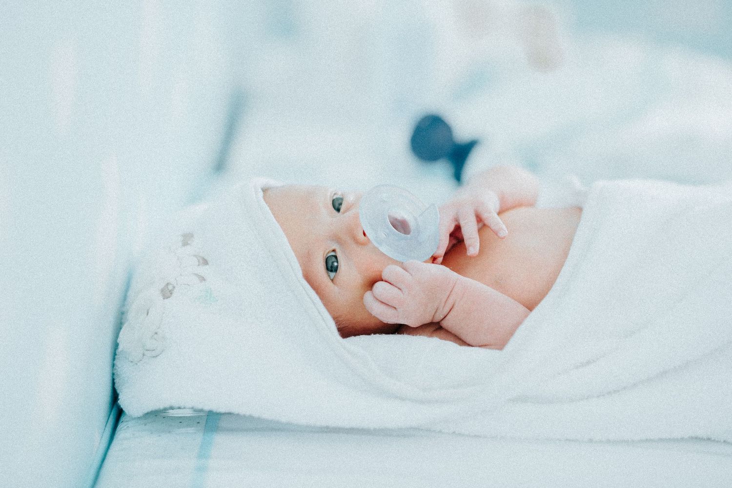 Close-up details of newborn baby's tiny features on white bedding.