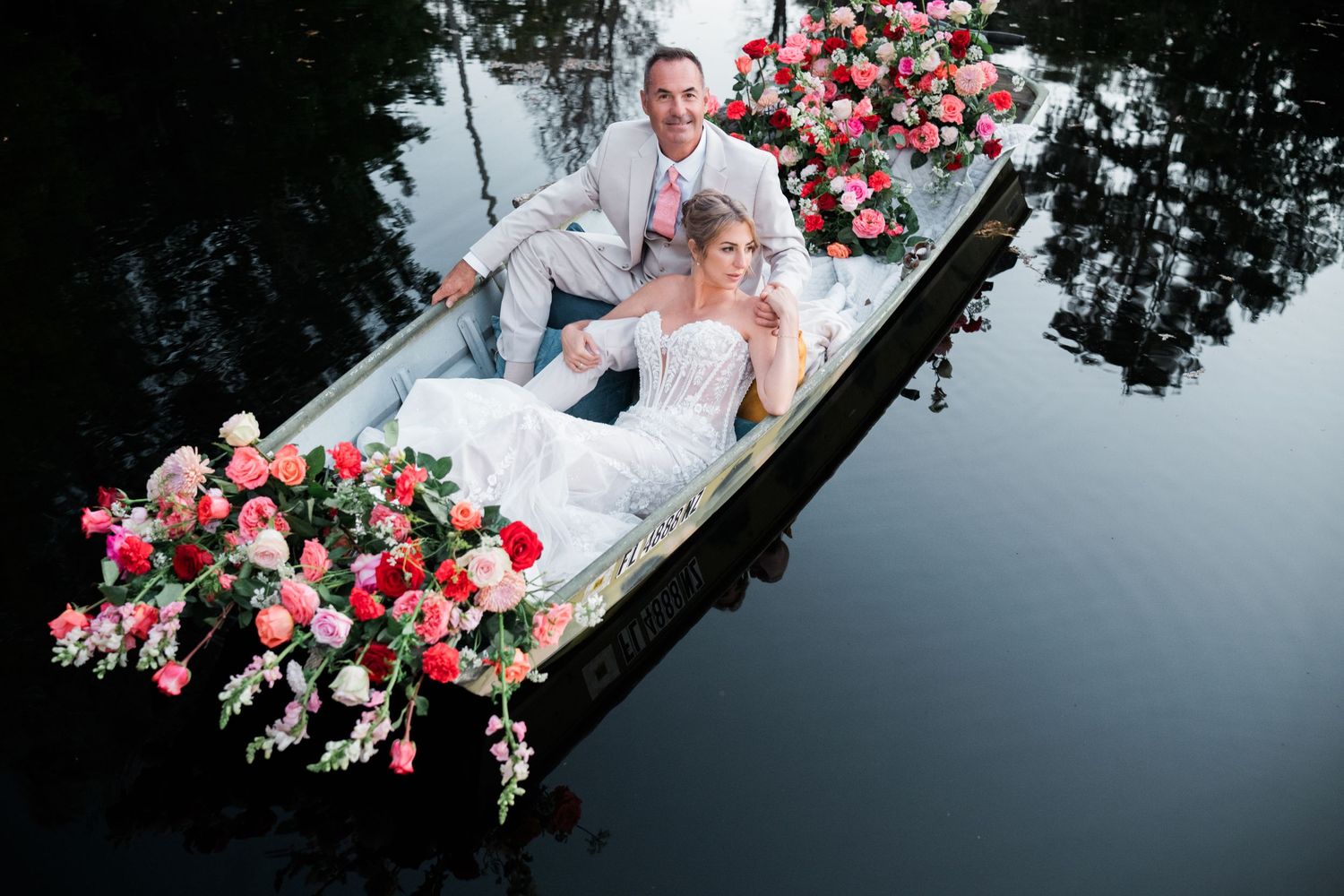 Dramatic reflection of pink roses and tree branches in dark water creating mirror effect.