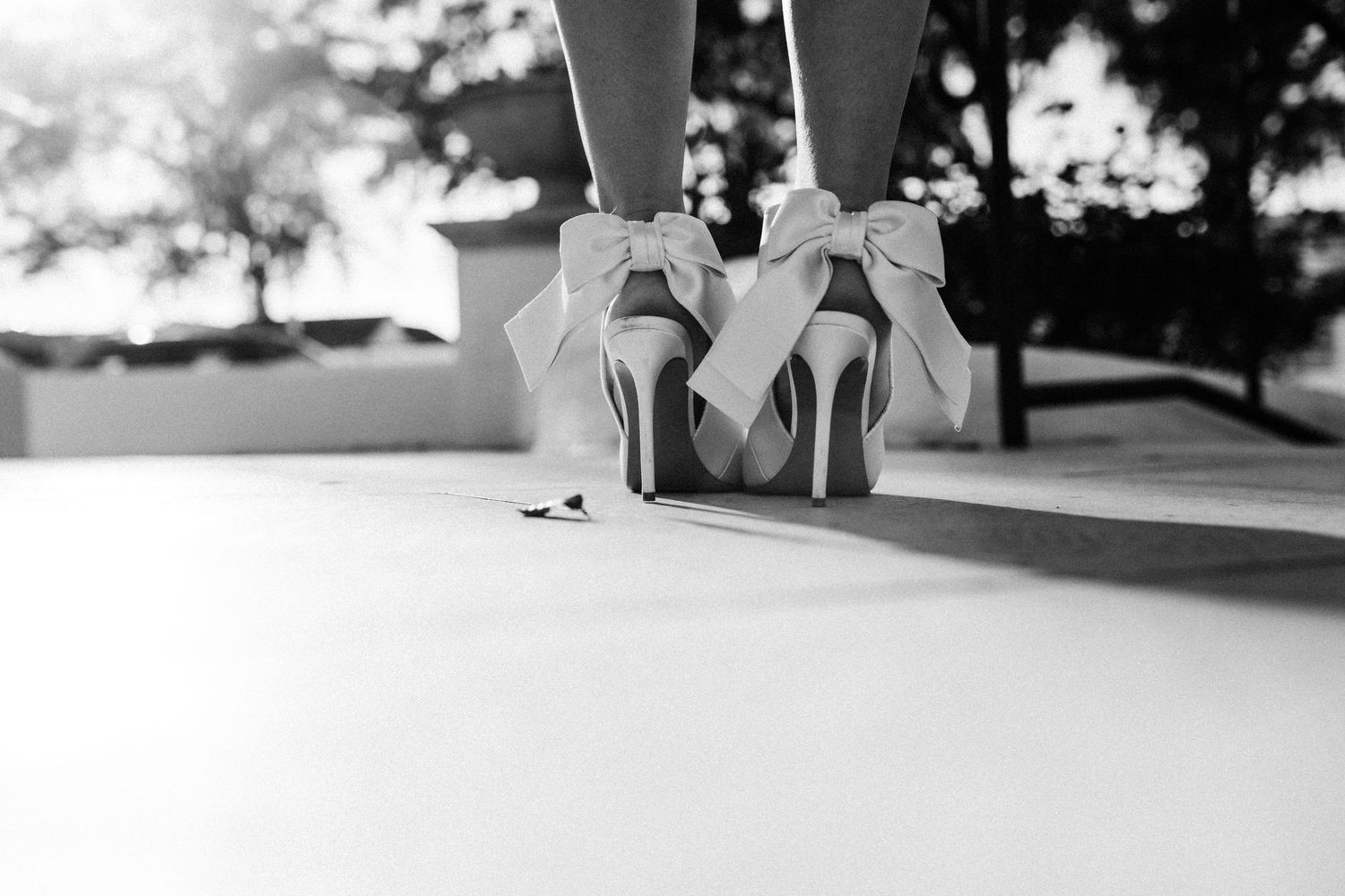 Black and white detail shot of feet in formal shoes on light floor.