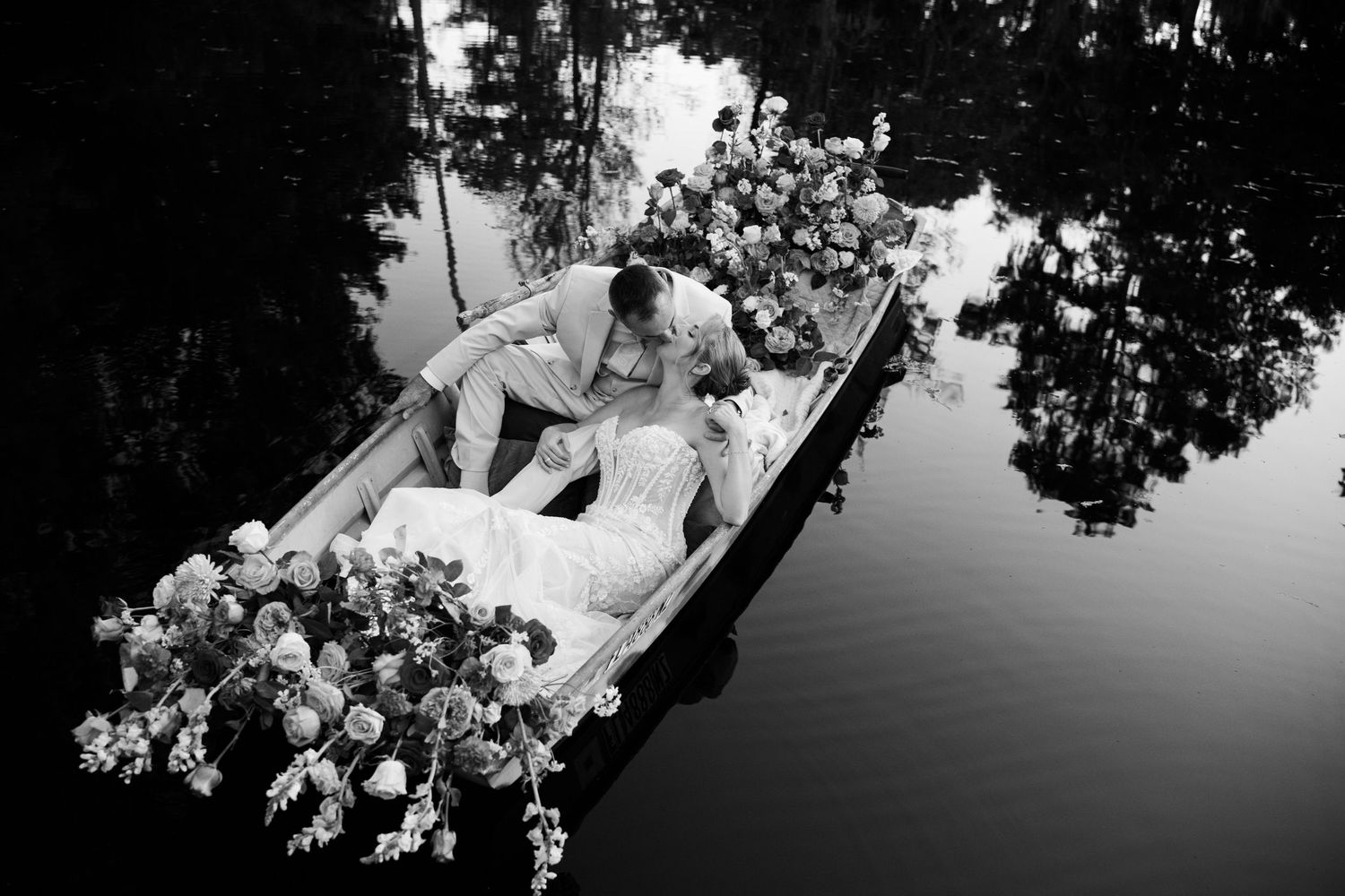 Black and white reflection of trees and flowers in still water creating artistic wedding ambiance.