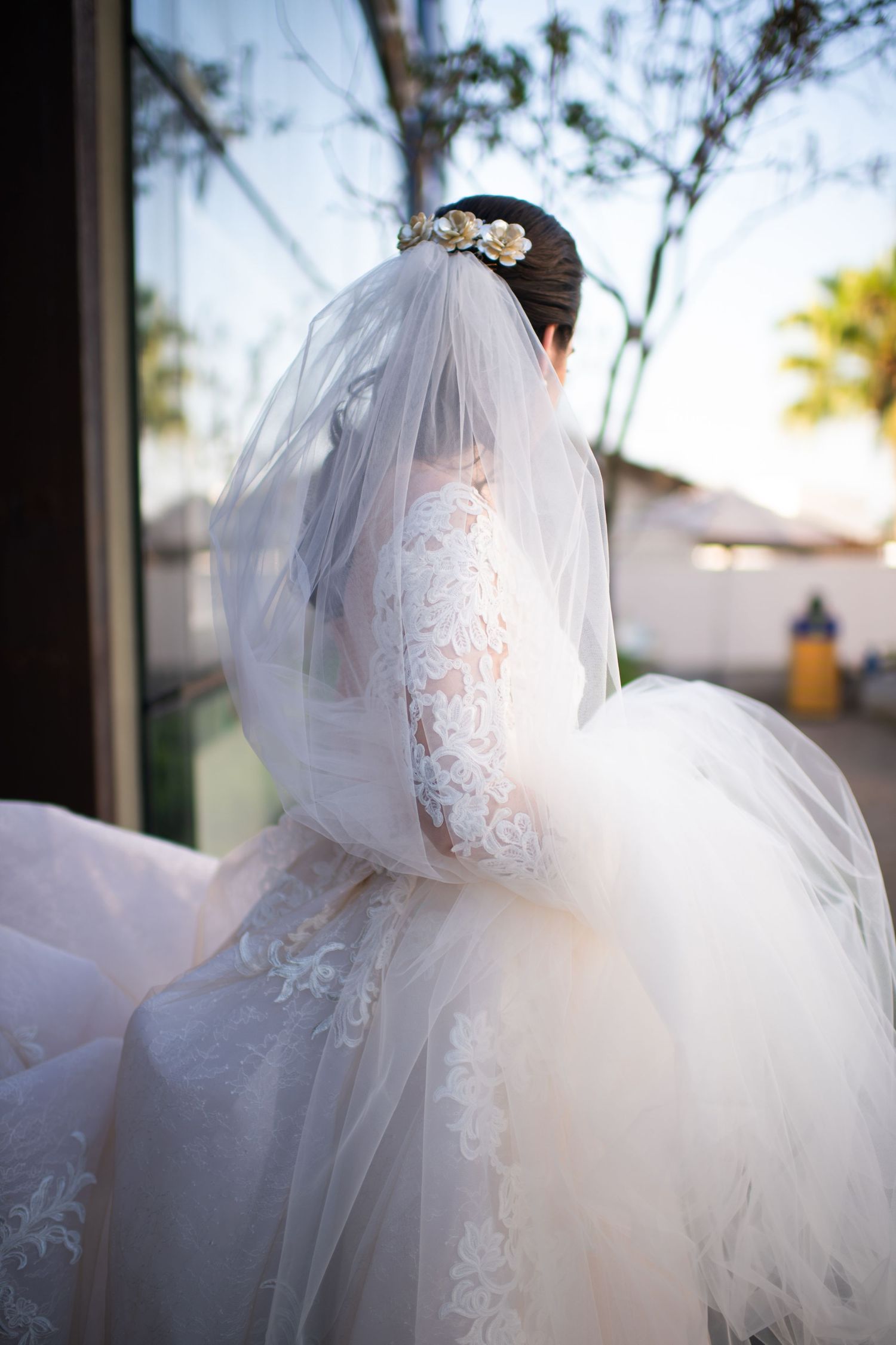 Dreamy outdoor portrait of a bride in flowing veil with sunlight filtering through trees.