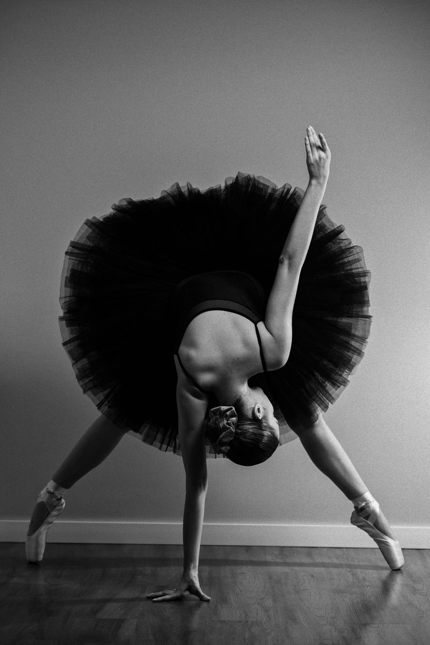 Black and white sequence of ballet dancer in tutu performing dynamic movements on floor.
