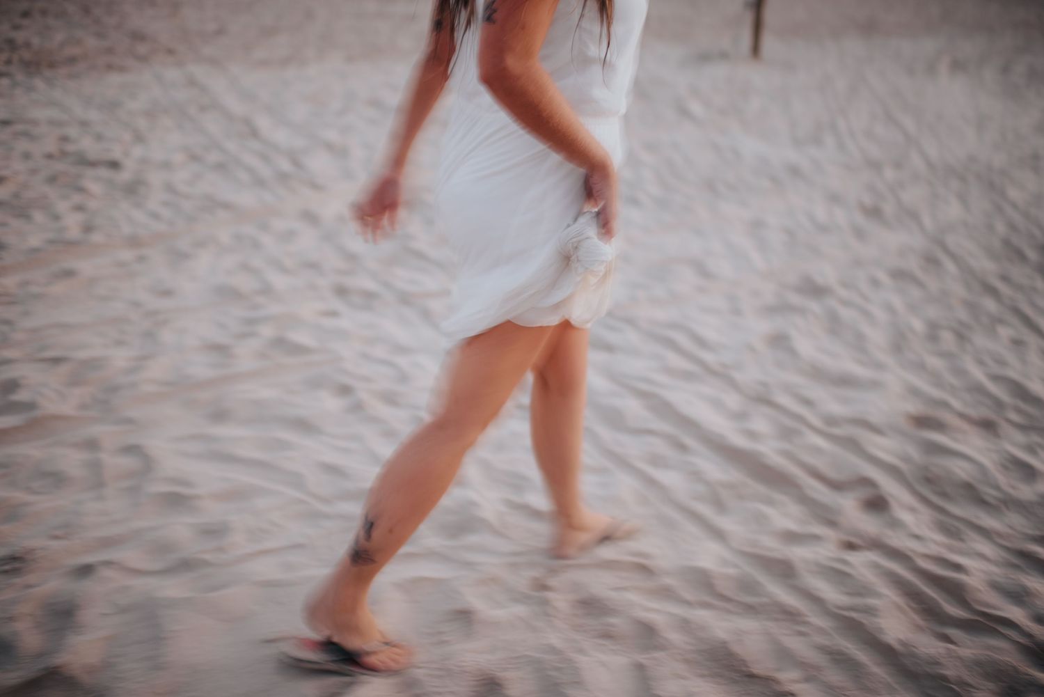 Footprints and movement captured in soft focus on sandy beach.