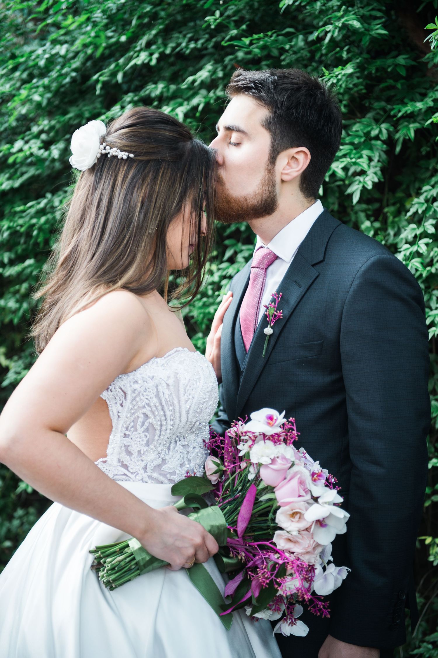 Romantic wedding portraits with pink and white bouquet against lush green background.