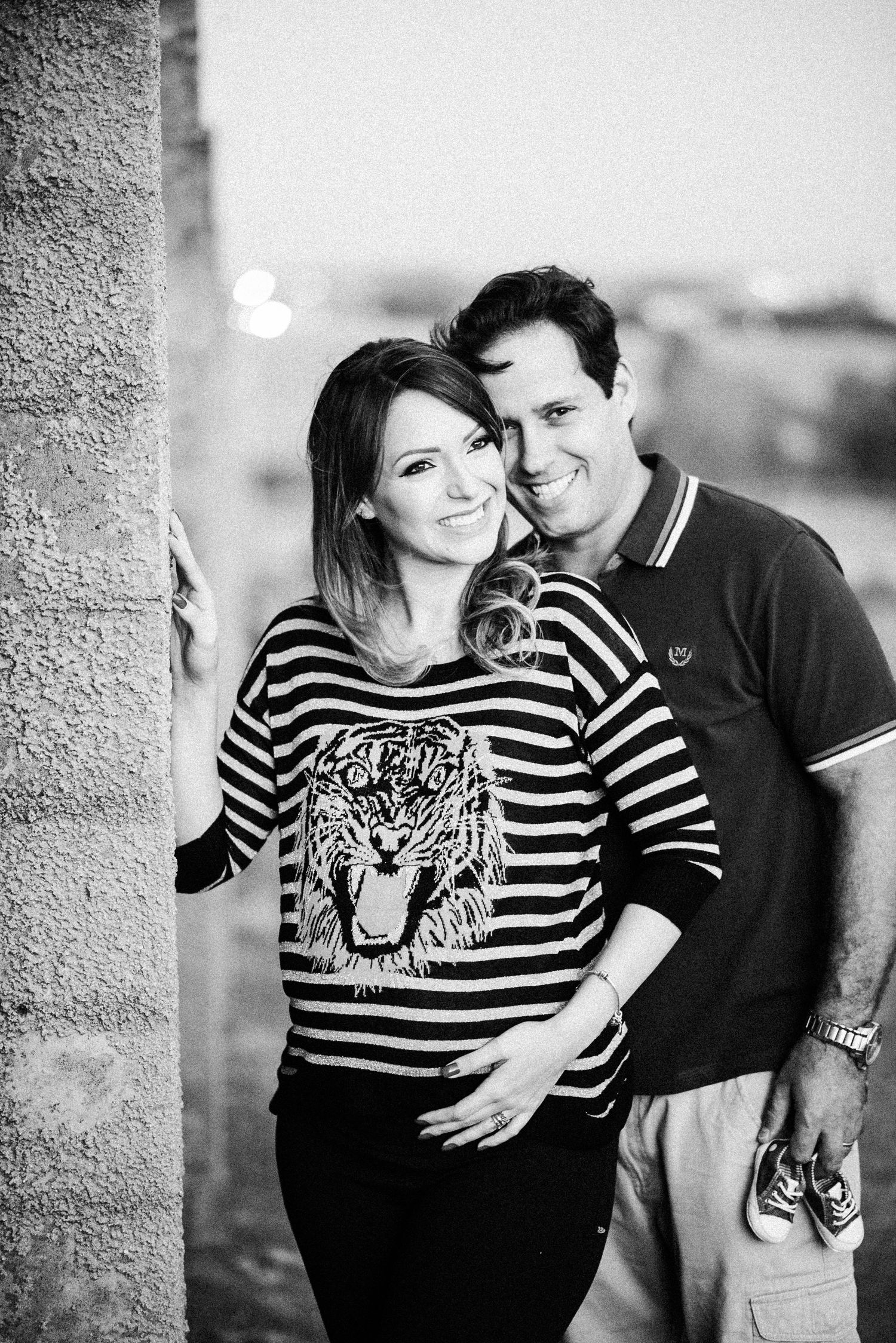 Black and white maternity photo series showing a couple in striped clothing embracing outdoors.