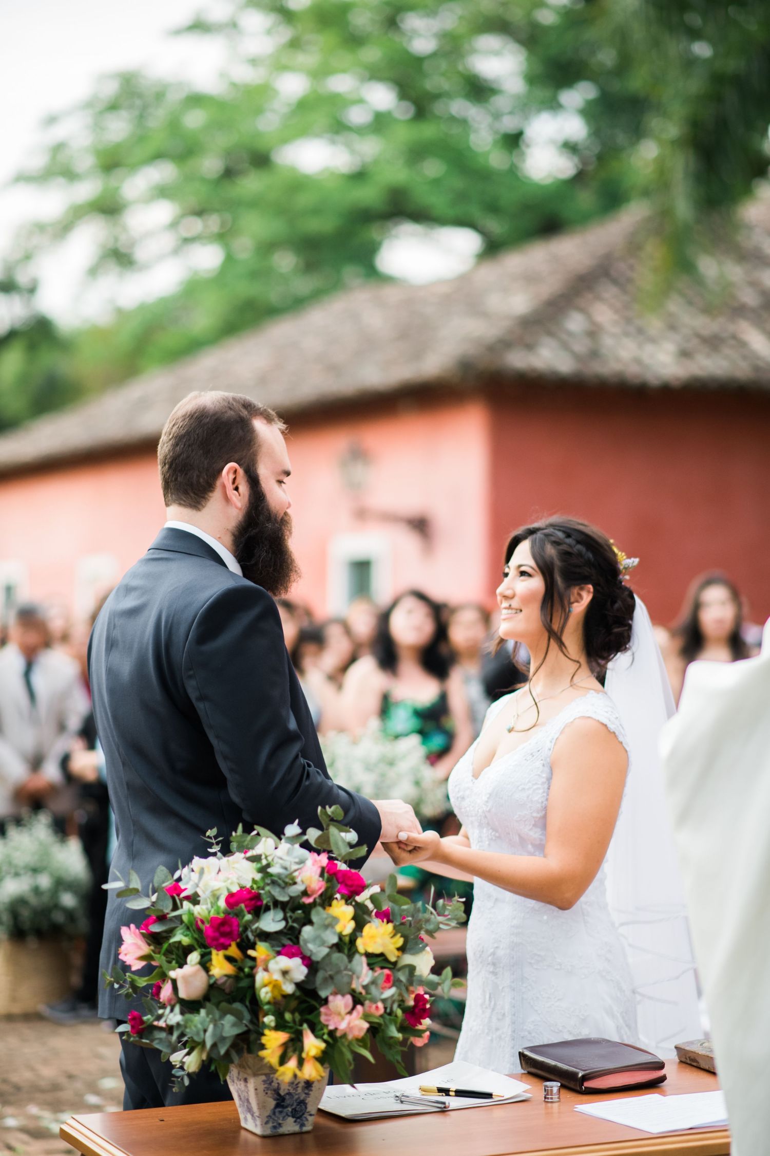 An outdoor wedding ceremony with colorful floral arrangements and guests watching the couple's special moment.