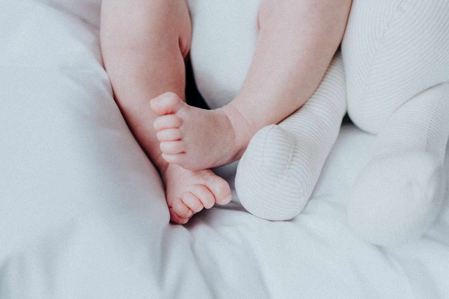 Newborn baby's feet resting on white blanket with blue accents.