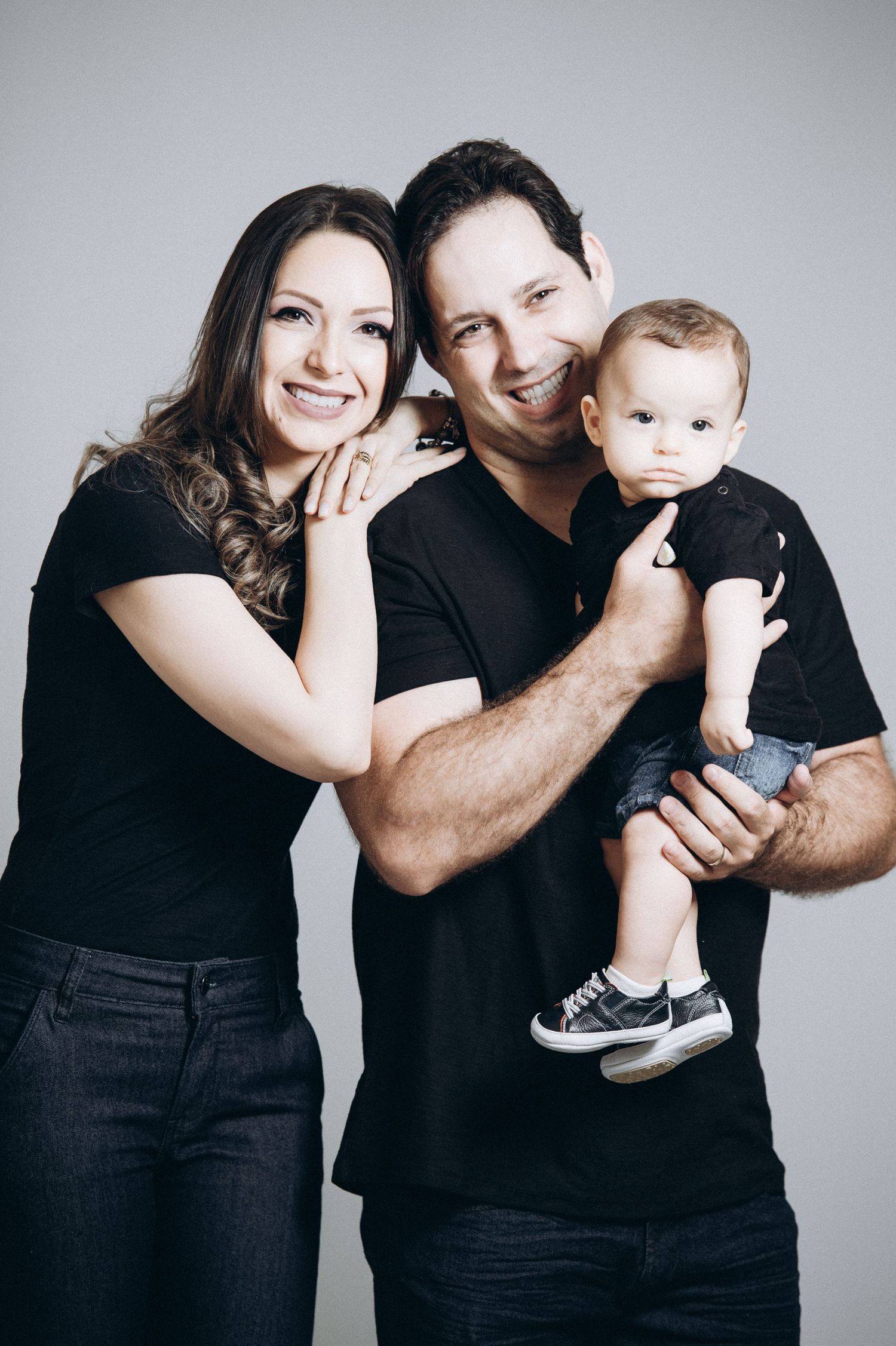 Family wearing coordinated black outfits pose together in a studio setting.