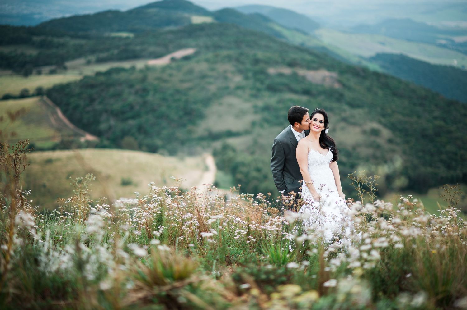 Wedding photography in mountain meadow with wildflowers and sweeping valley views.